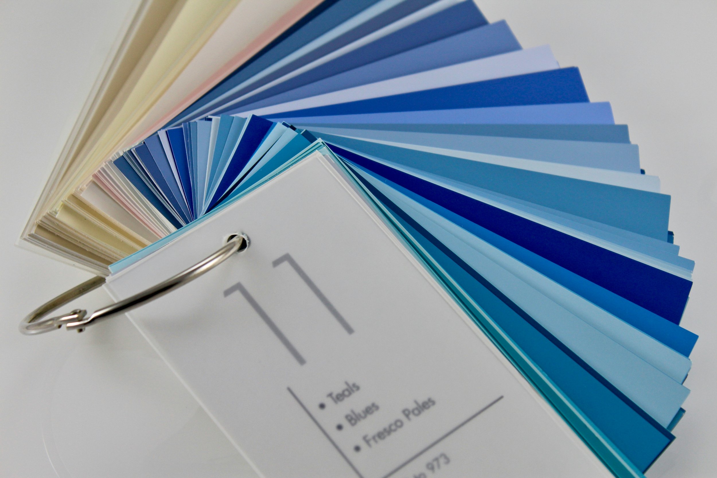 Color swatch sample book with various shades of blue, pink, and cream, attached to a ring binder, titled '11' on the front.