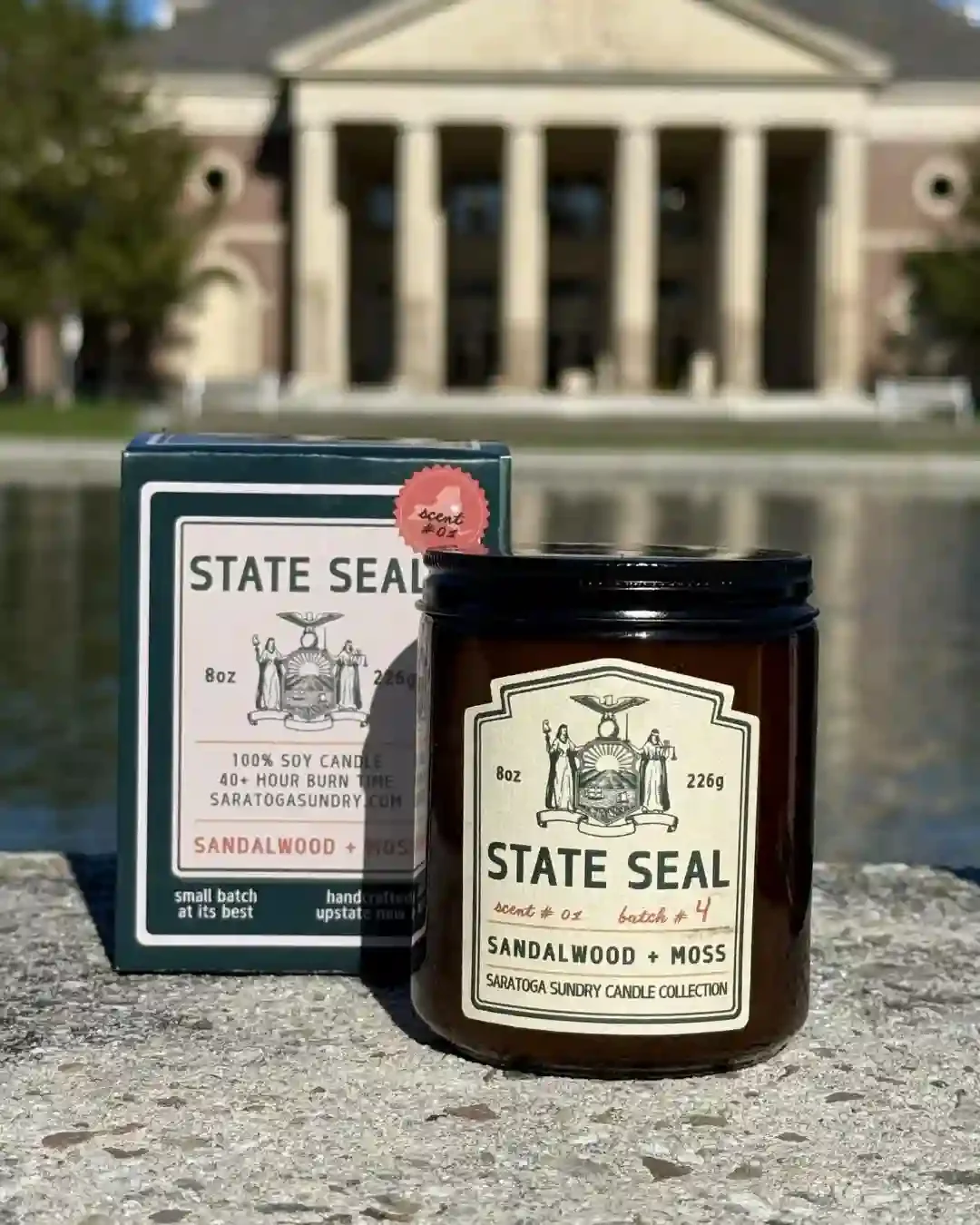 State Seal  candle and gift box from Saratoga Sundry in front of the Hall of Springs in Saratoga Springs NY.webp