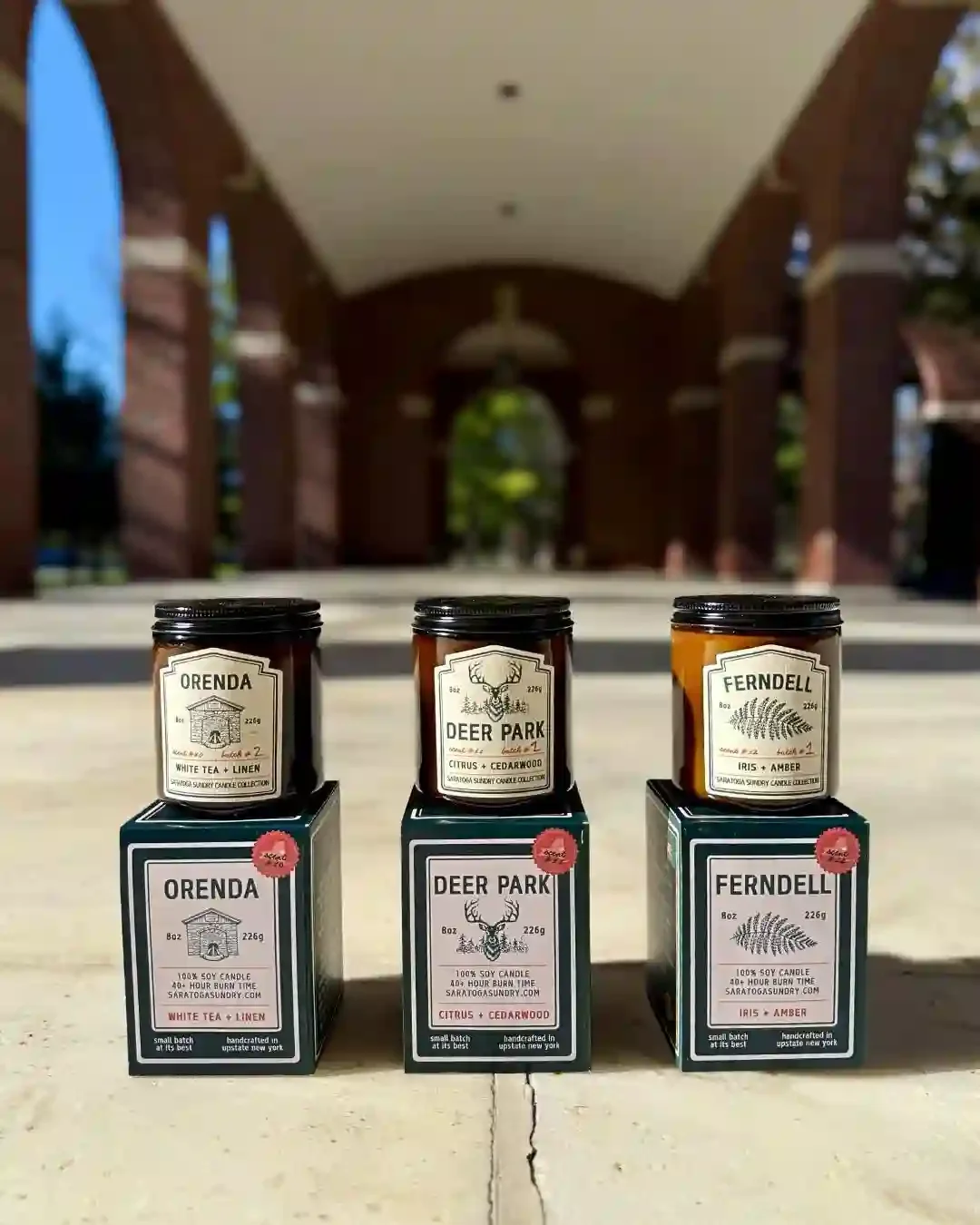 Trio of three candles and gift boxes from the Saratoga Sundry candle collection shot in the Hall of Springs in Saratoga Springs NY.webp