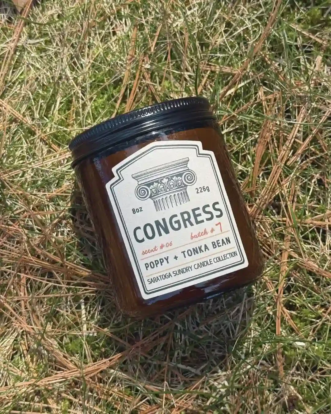Congress soy candle in amber jar from Saratoga Sundry laying in grass.webp