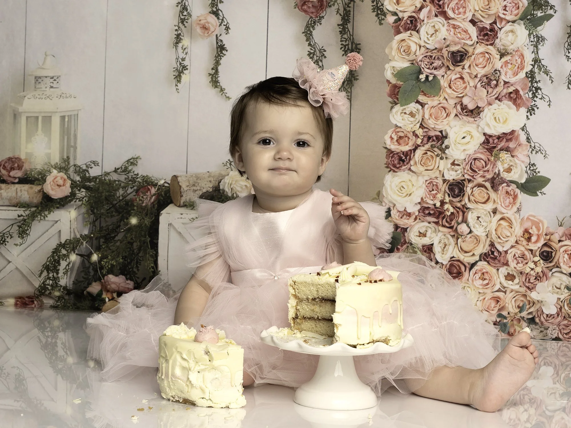 one year old girl in a pink dress cake smash picture with floral background