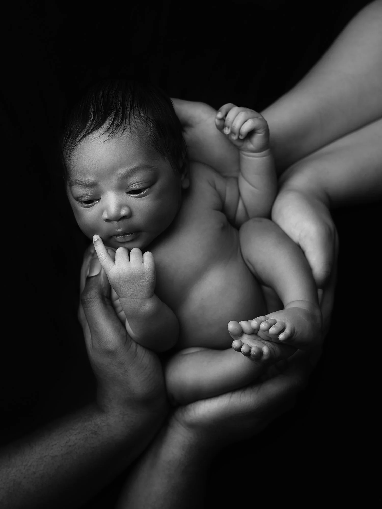 b&w picture of a newborn baby in parents hands