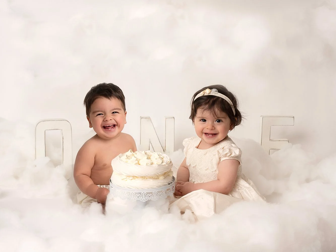 boy and a girl twins first birthday posing with a cloud theme and white cake