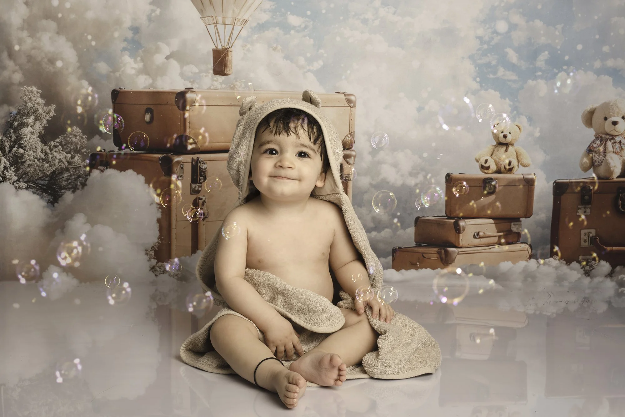 toddler sitting with bear ears towel with hot air balloon theme background