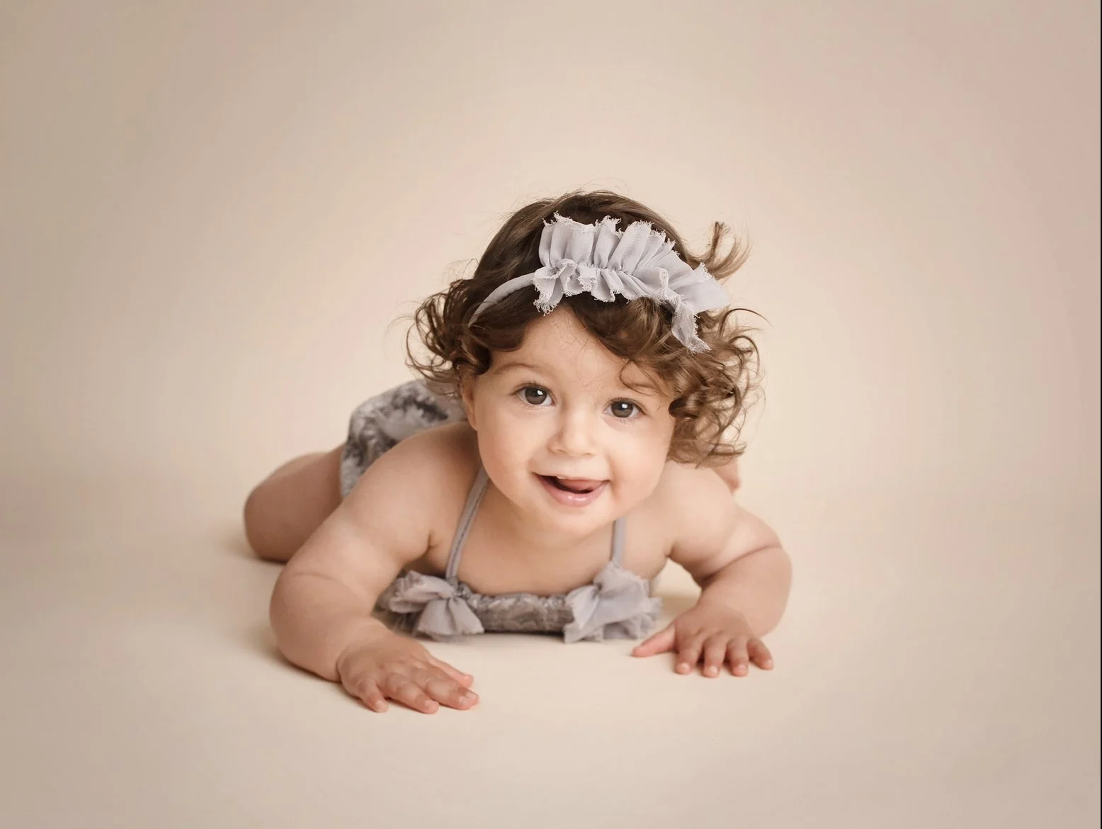 toddler posing on a floor in a grey outfit