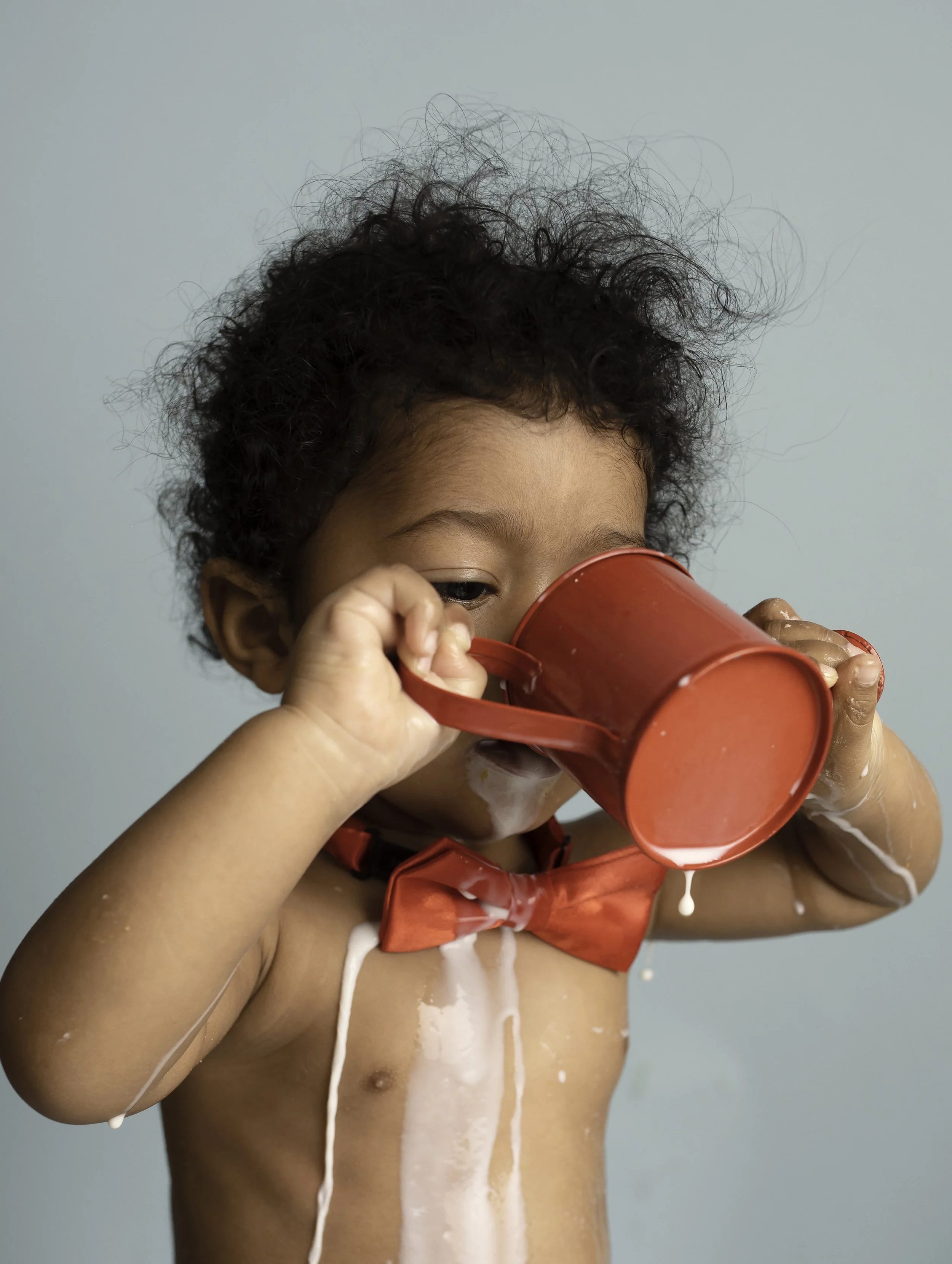child drinking milk from a red vintage cup with a blue background
