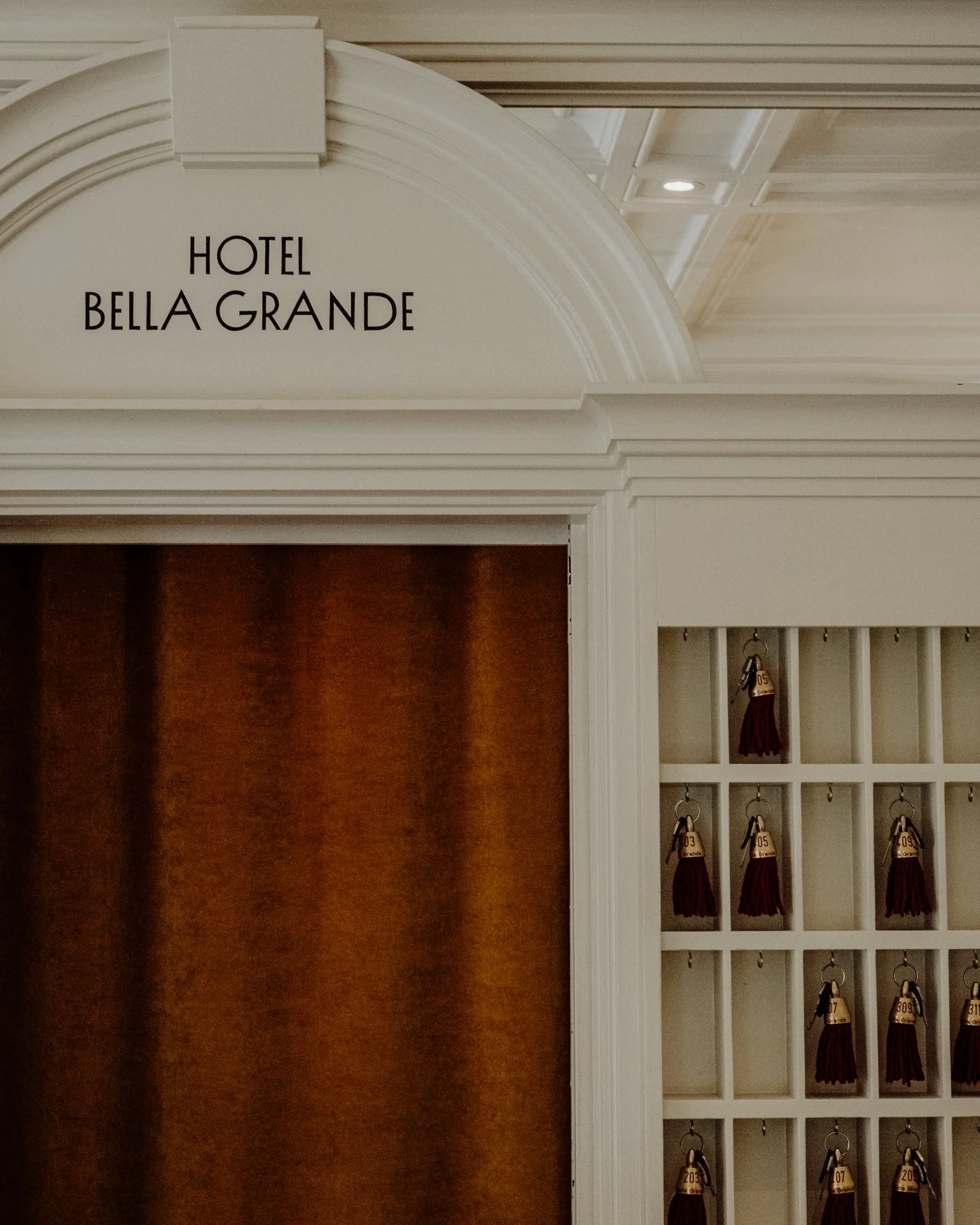 Sign for Hotel Bella Grande next to a key lockboard with numbered keys.