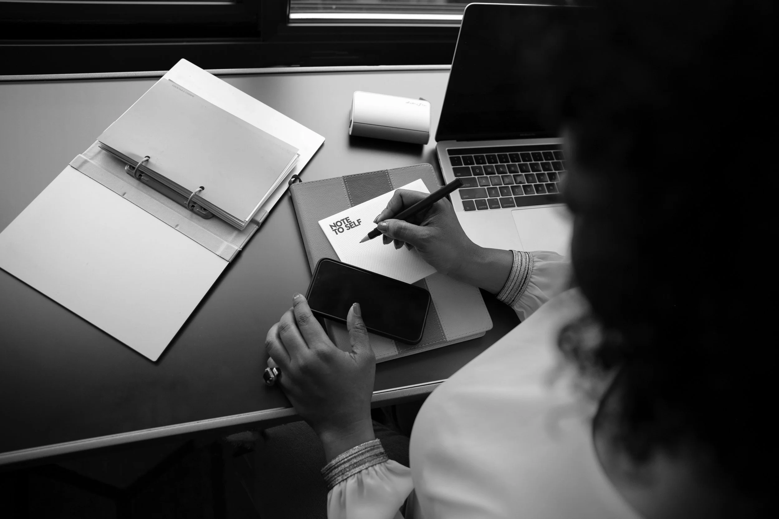 Cassandra Shepard at her desk with a journal and laptop, reflecting her strategic approach to executive coaching and leadership planning.