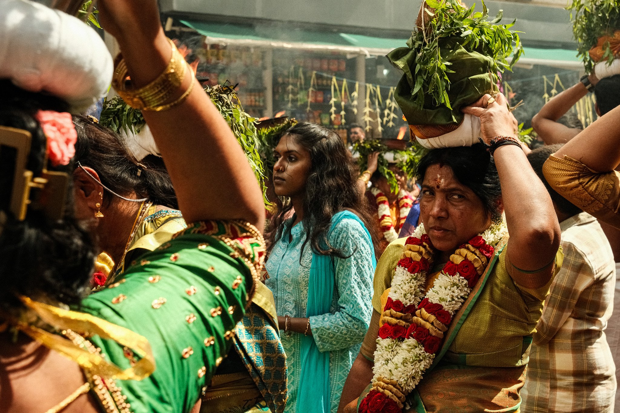 Hierarchies de personnes dans une cérémonie balinaise, portant des vêtements traditionnels colorés, avec des garlands de fleurs.