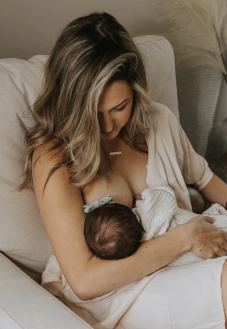 A mother receiving postpartum support from Kaiser doula Kalista Zubiate breastfeeds her newborn in LA County.