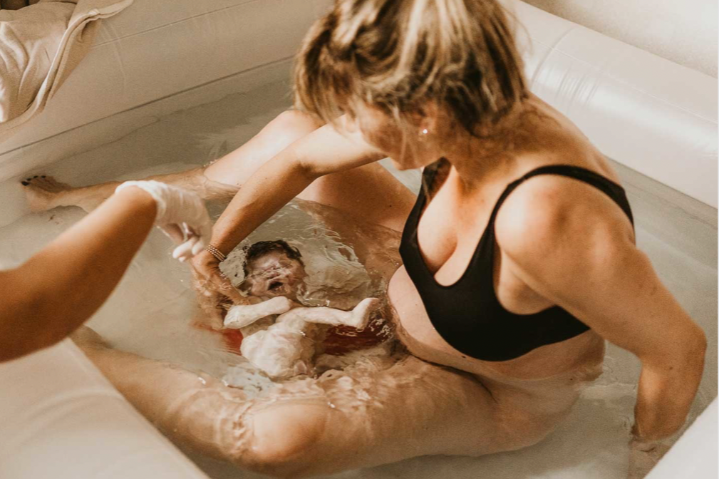 A woman delivers her baby during a water birth, having prepared for her birth experience with HypnoBirthing instructor Kalista Zubiate.