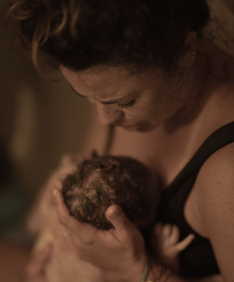 A mother holds her newborn after receiving birth support from Nurture The Divine in Whittier, CA.