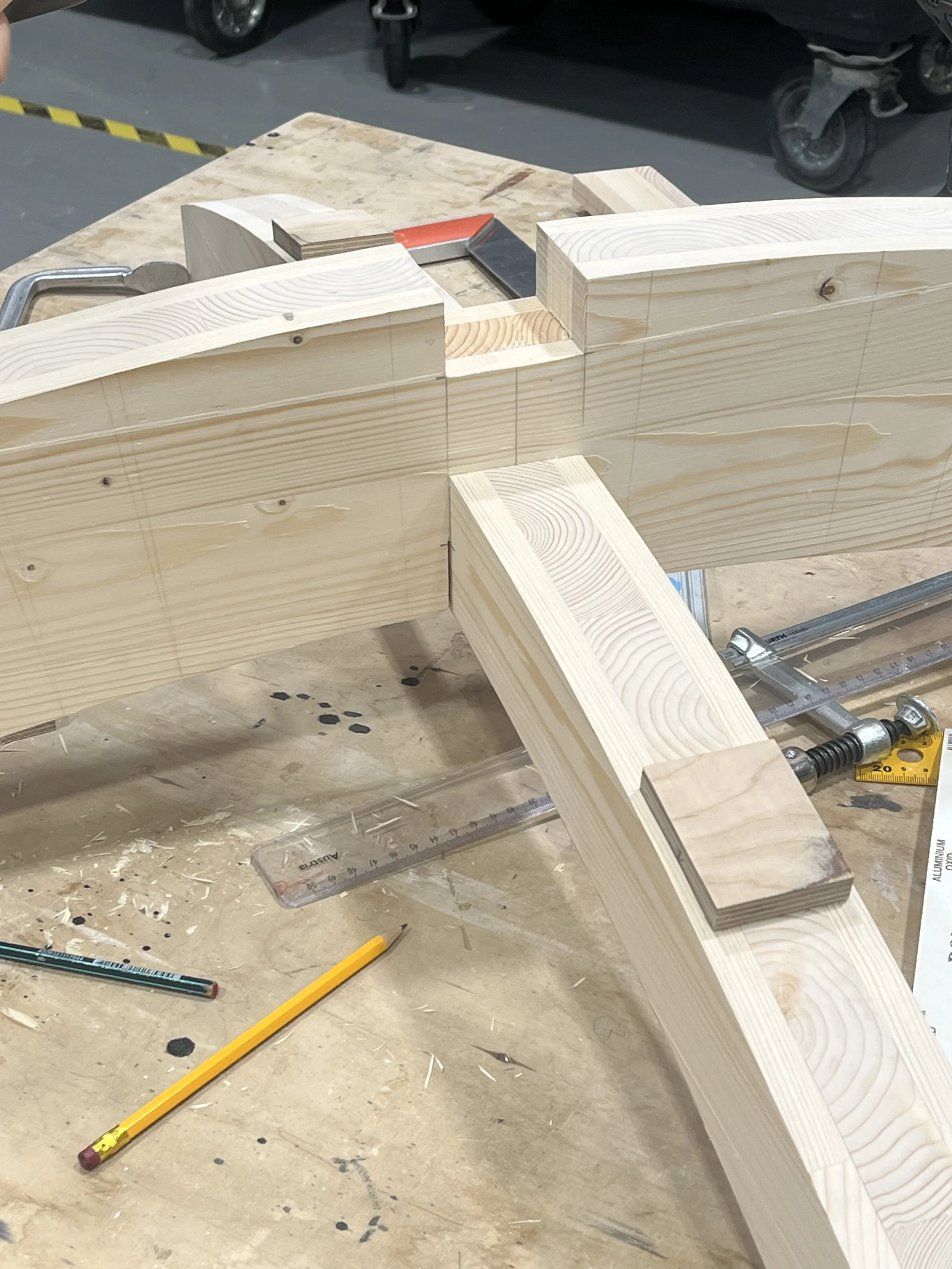 Wooden woodworking project in progress with various measuring tools and clamps on a workbench.