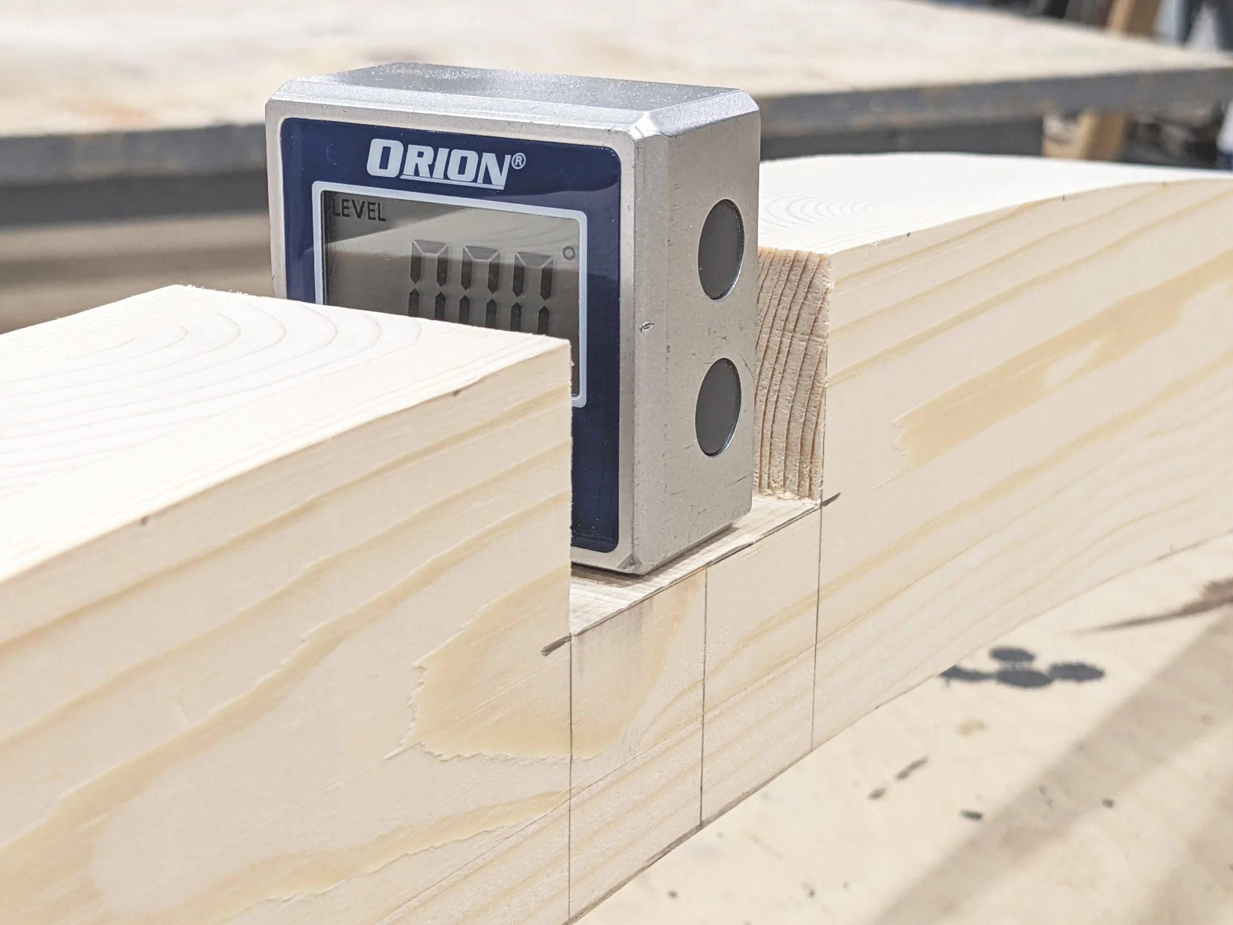A digital level placed on a wooden beam at a construction site.