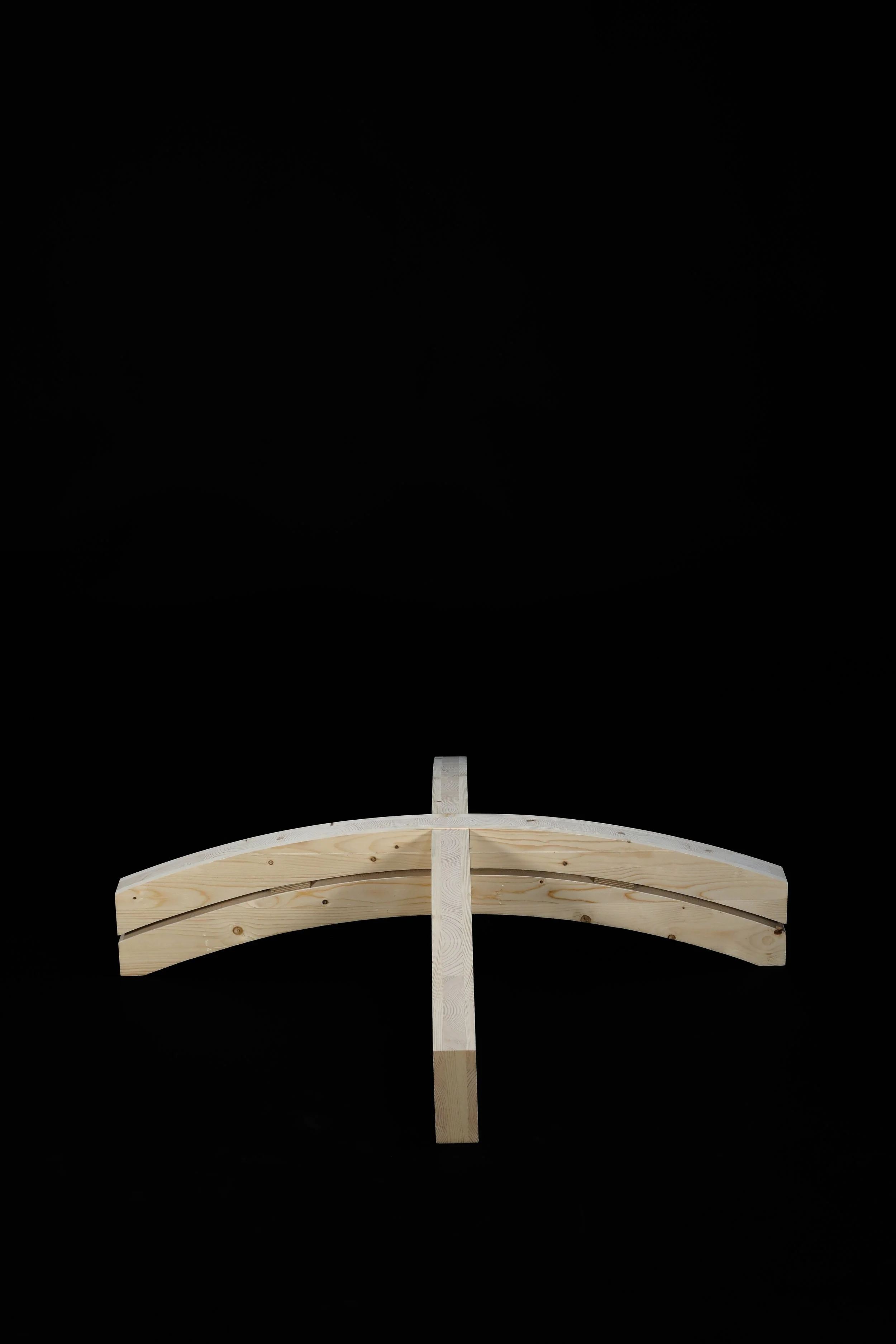 Wooden cross construction with curved beams and central vertical support on black background.