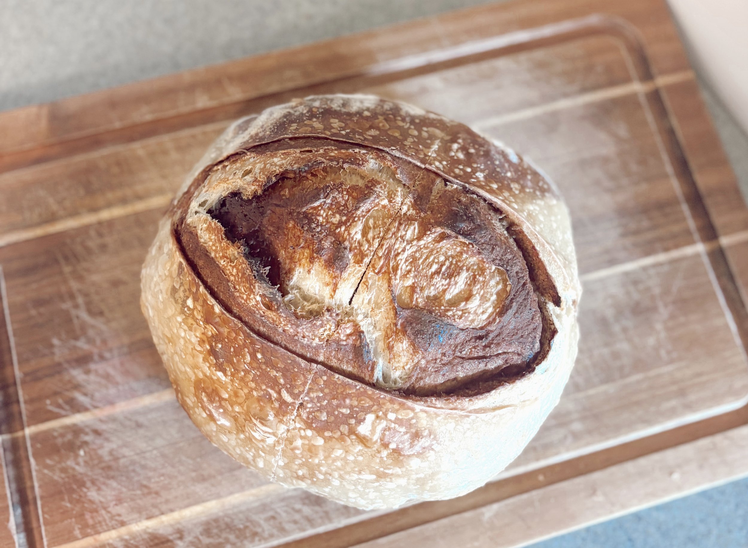 Round loaf of sourdough bread on a wooden cutting board.
