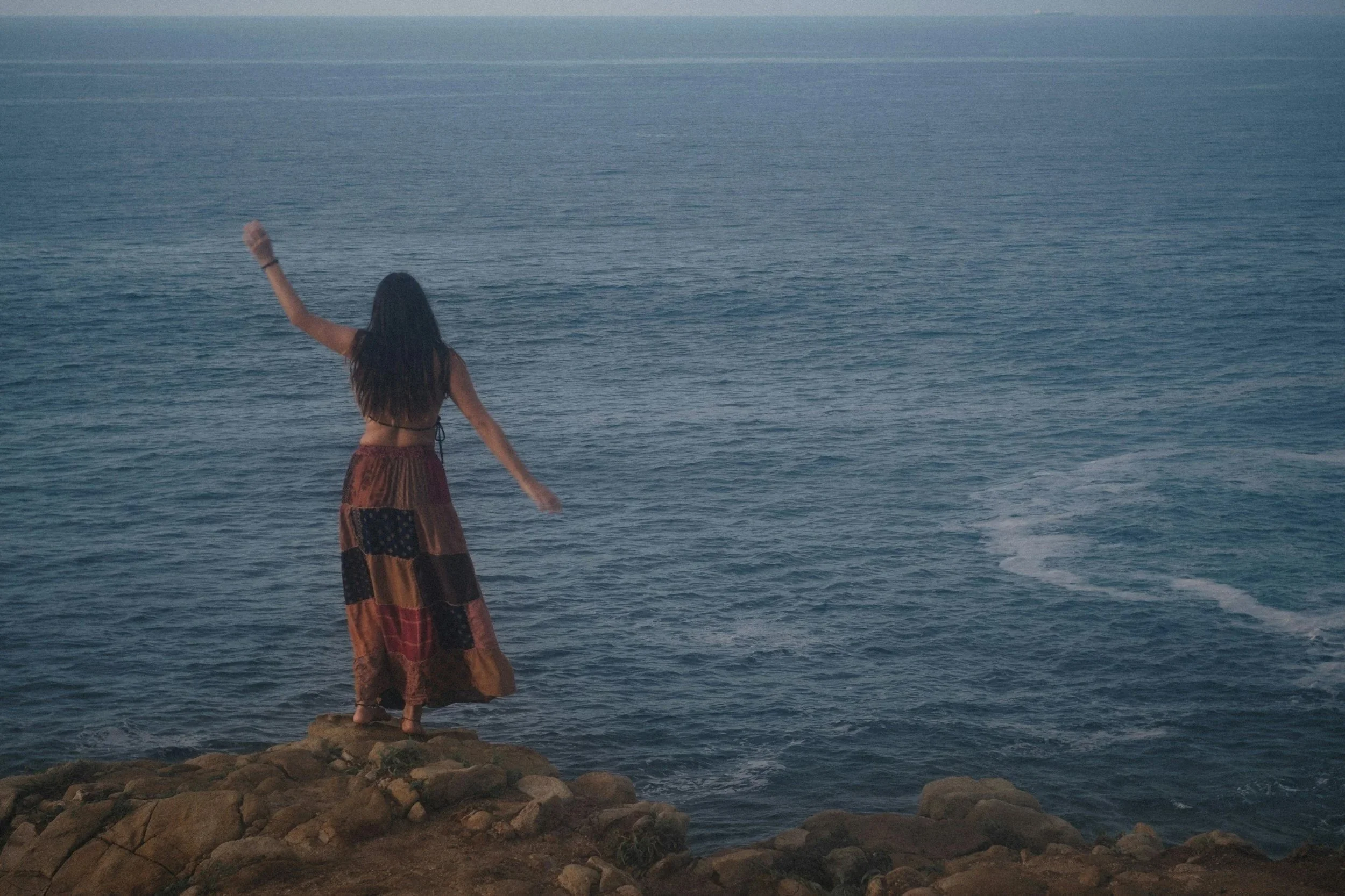 Woman standing on a cliff overlooking the Pacific Ocean in California, representing grounding, emotional regulation, and inner parts integration in EMDR and parts work therapy.