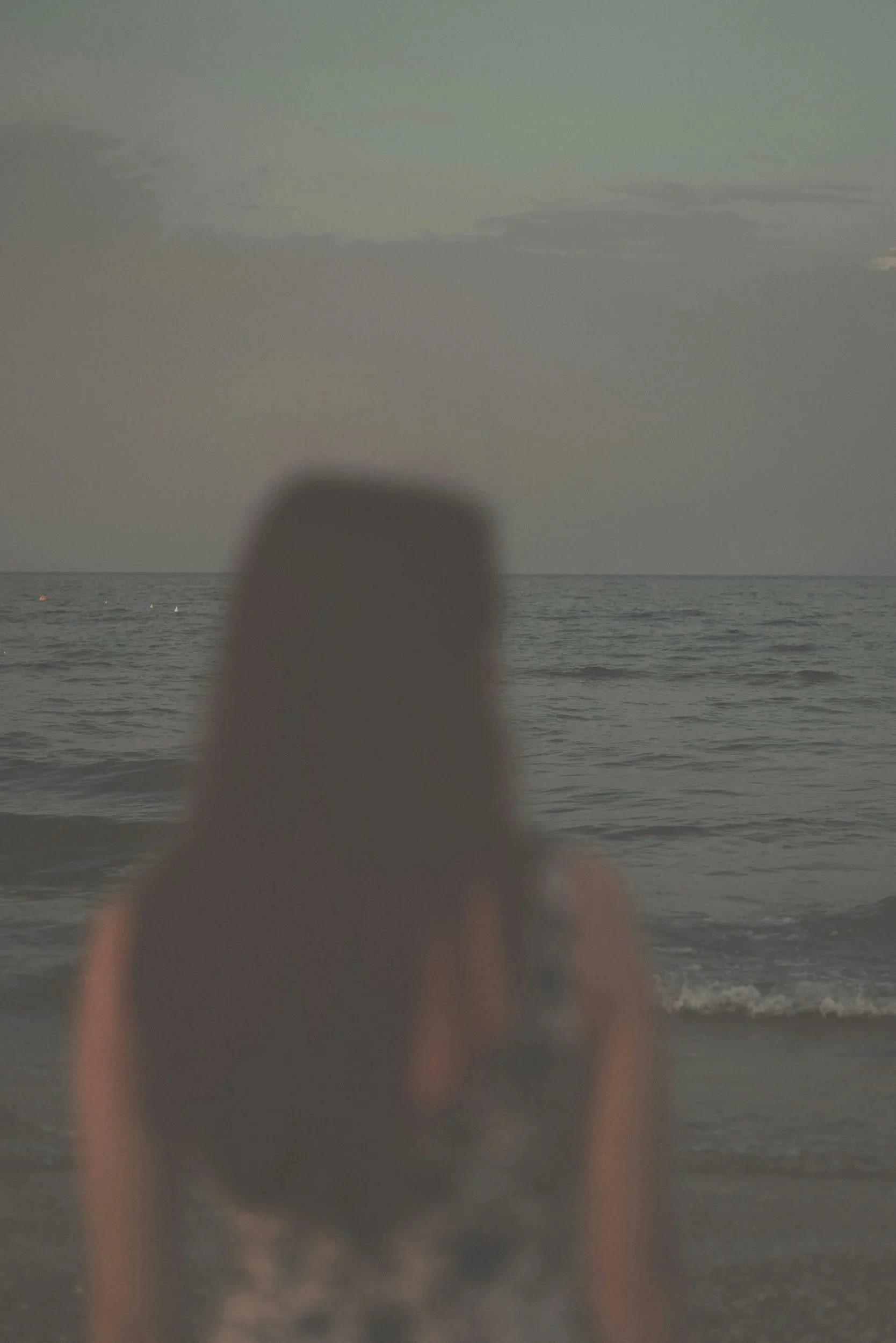 Woman looking out at the ocean on a calm California evening, evoking peace, reflection, and emotional healing after her parts work therapy in San Diego, California.