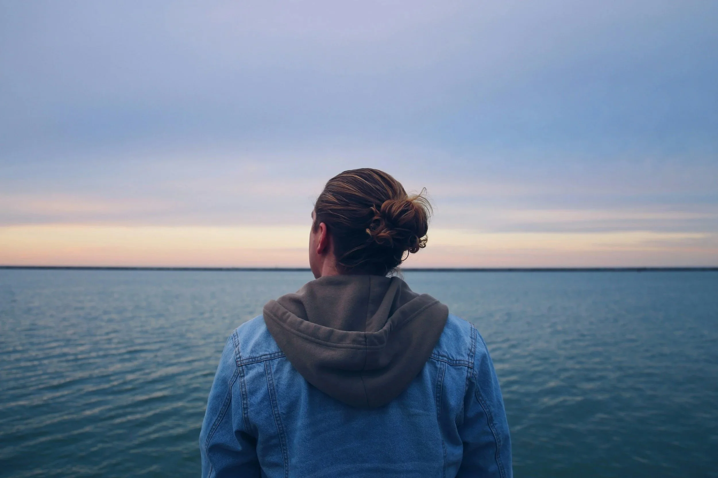 Male in his 20s looking out over the ocean at sunset, representing grounding, nervous system regulation, and inner parts integration in EMDR and parts work therapy.