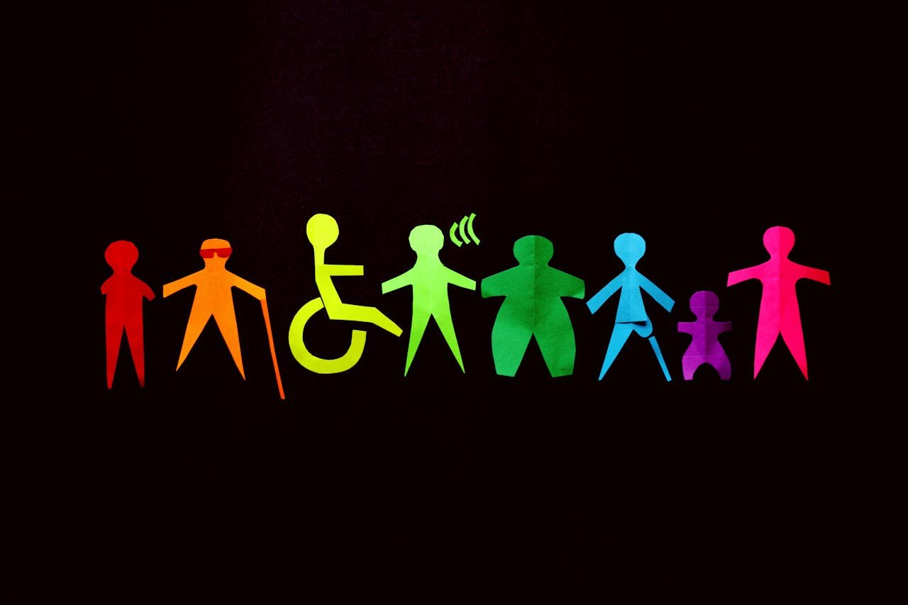 Colorful paper cutouts of diverse human figures representing different abilities and body types on a black background.