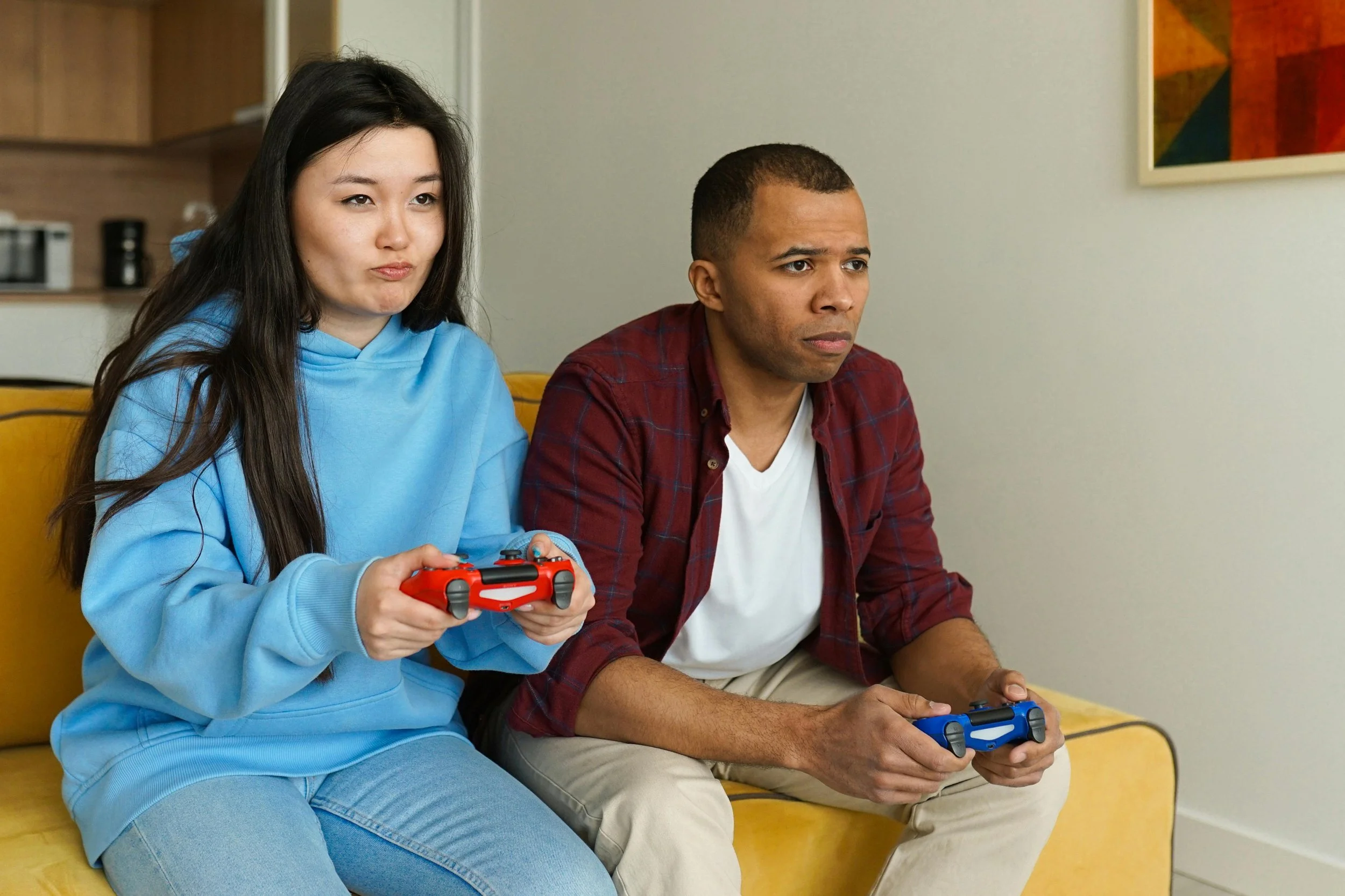 A couple sitting on a couch holding came controllers engaged in playing a video game