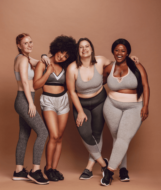 "Four women of various races and body shapes smiling standing with arms around each other expressing pride and confidence in themselves."