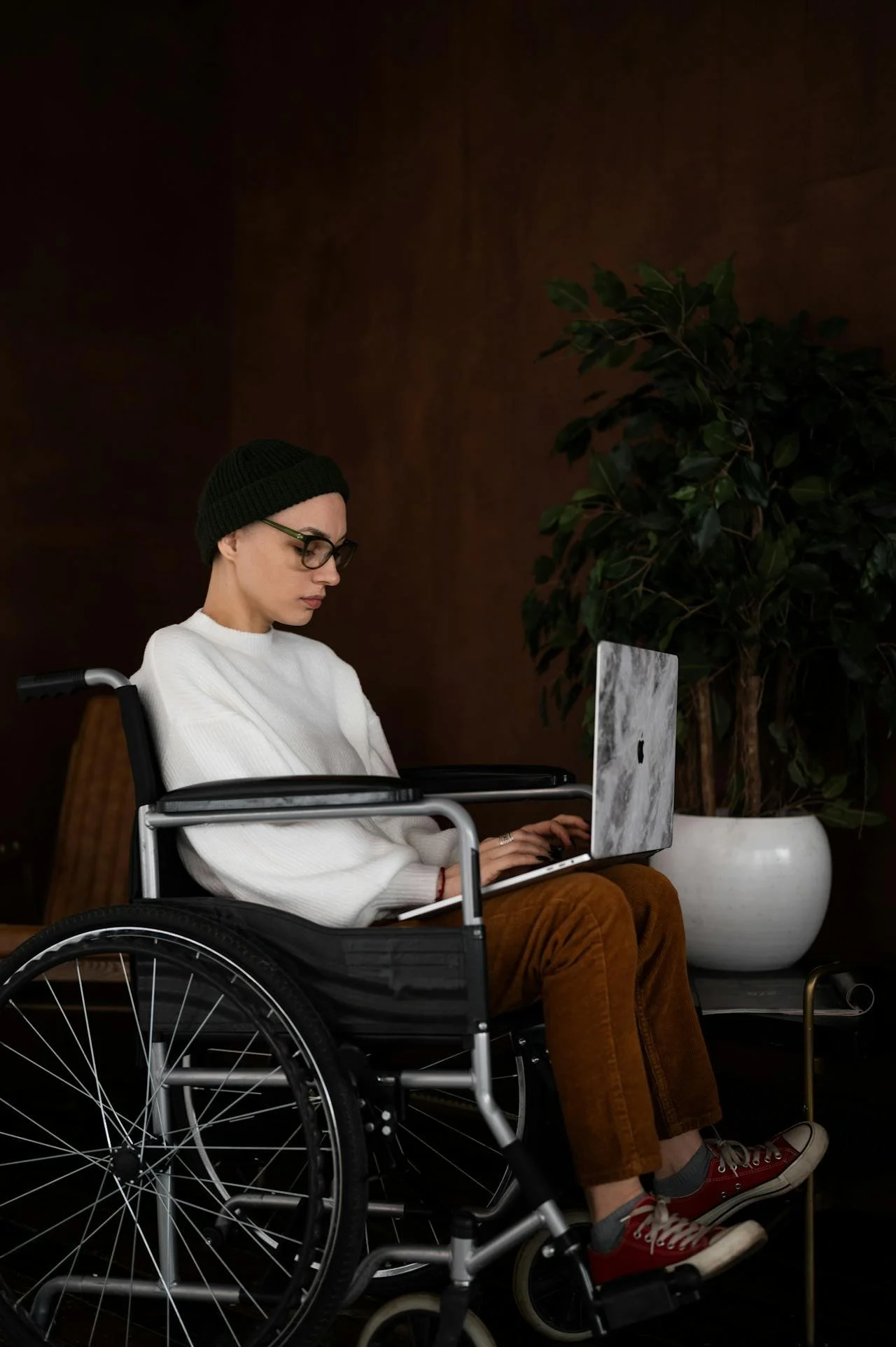 A person sits in a wheelchair with an open laptop