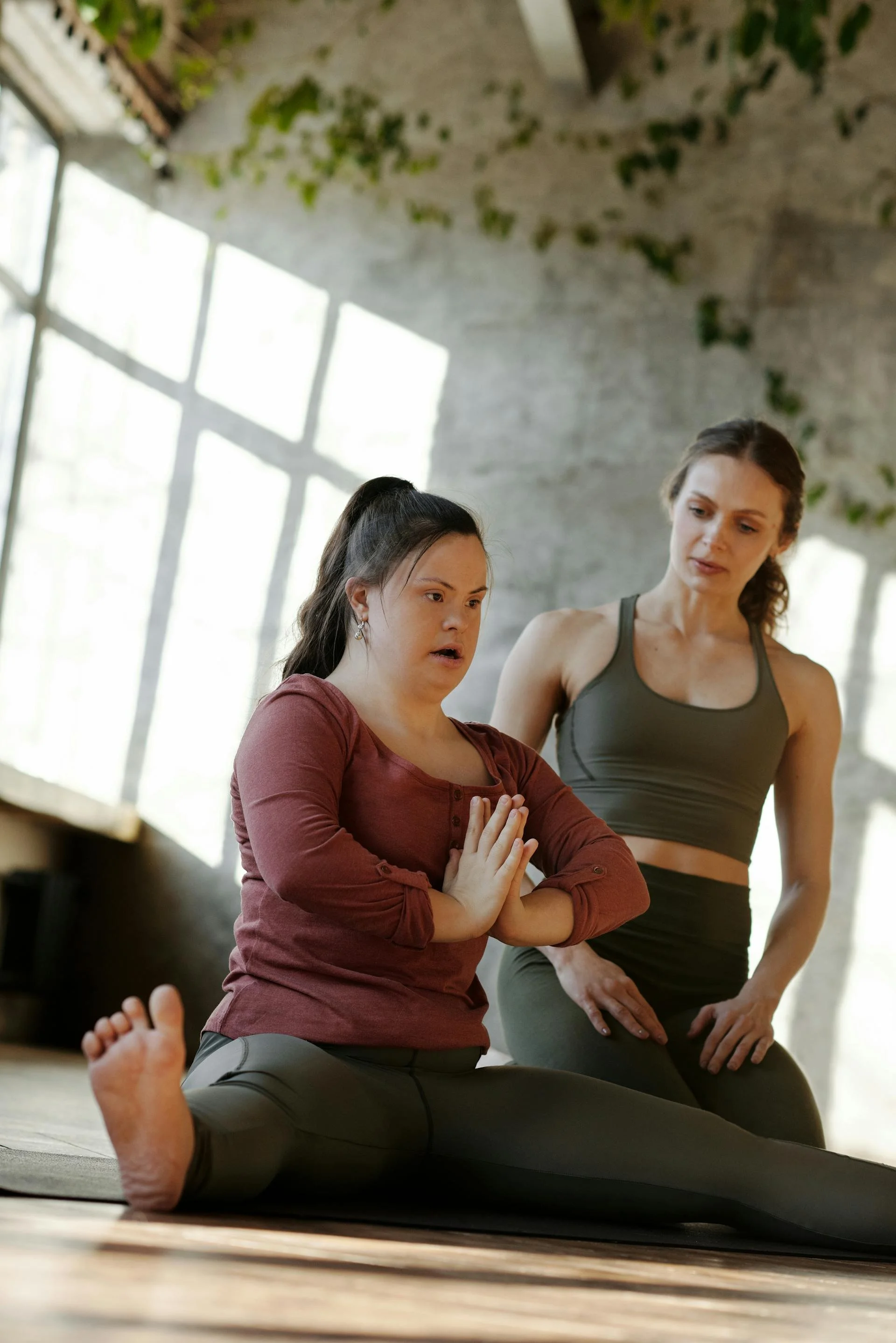 A teacher and student in a yoga studio work on a pose