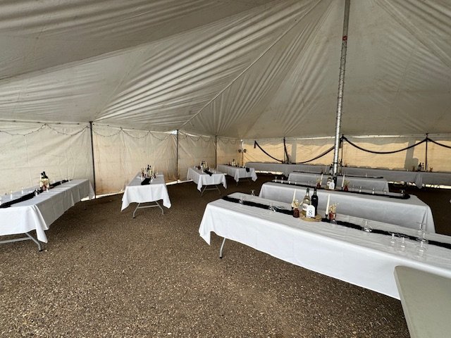 Reception tables arranged inside the event tent before guests arrive.