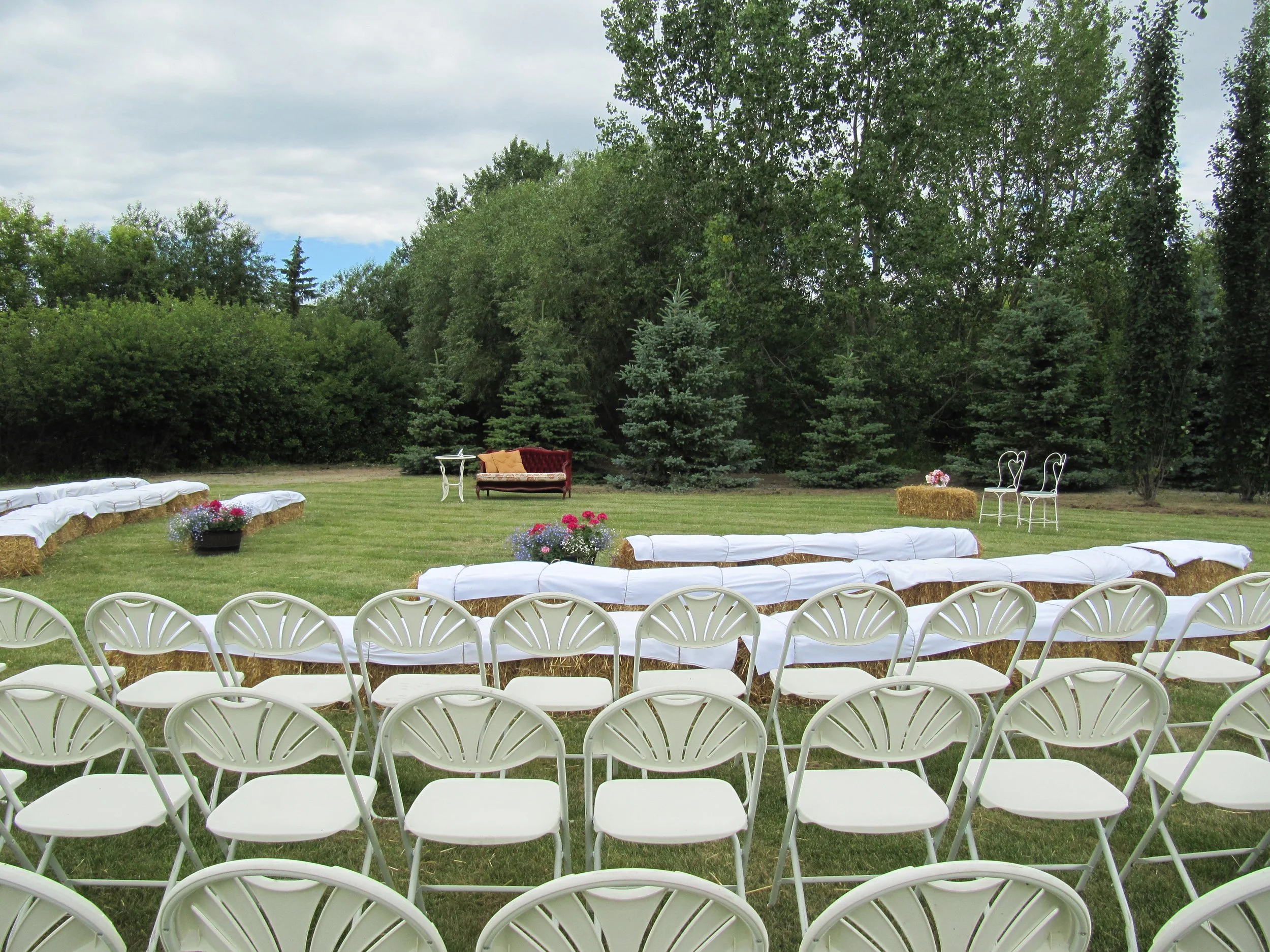 Outdoor reception are with seating surrounded by lush trees and prairie greenery