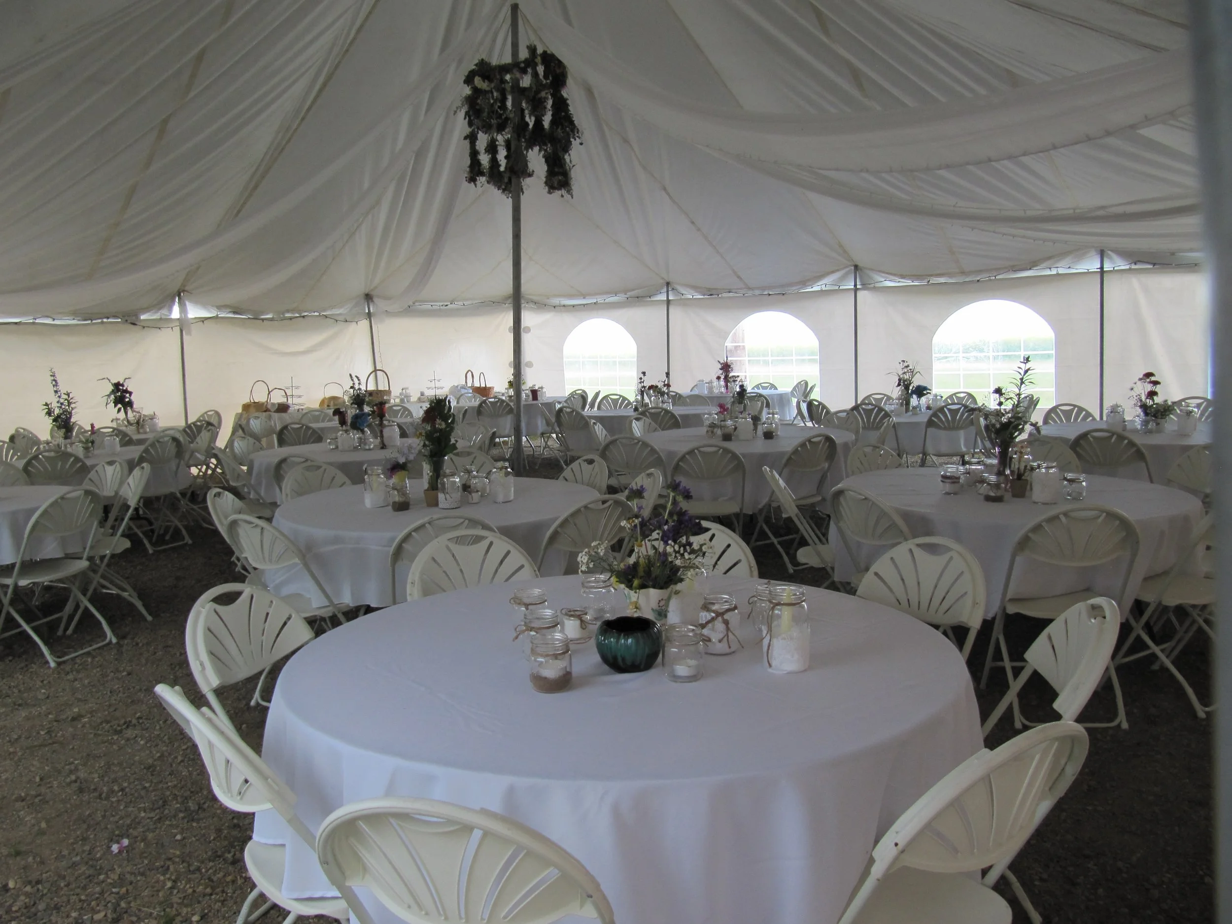 Reception tables with white linens inside the elegant event tent.