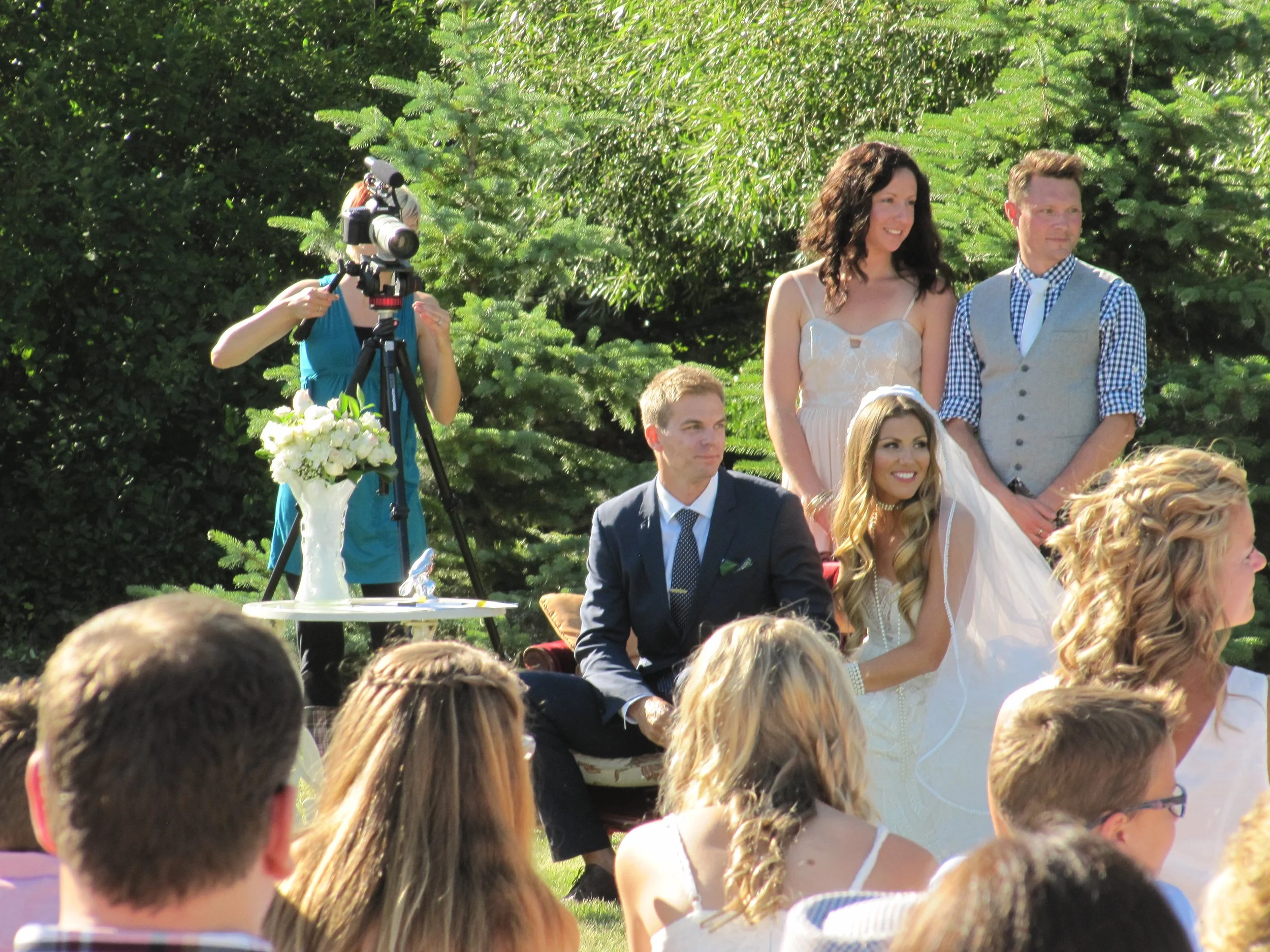 Bride and groom sitting together while their photographer captures photos.