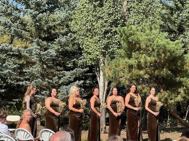 Bridesmaids standing together in brown dresses hold bouquets