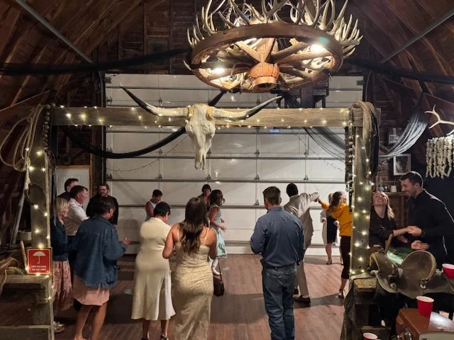 Wedding guests gathered near the dance floor beneath an archway with a mounted skull