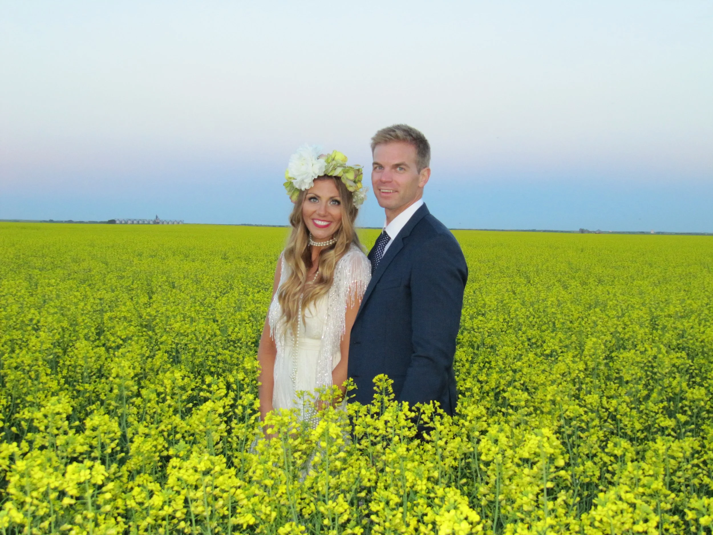 Bride and groom standing together in a blooming canola field
