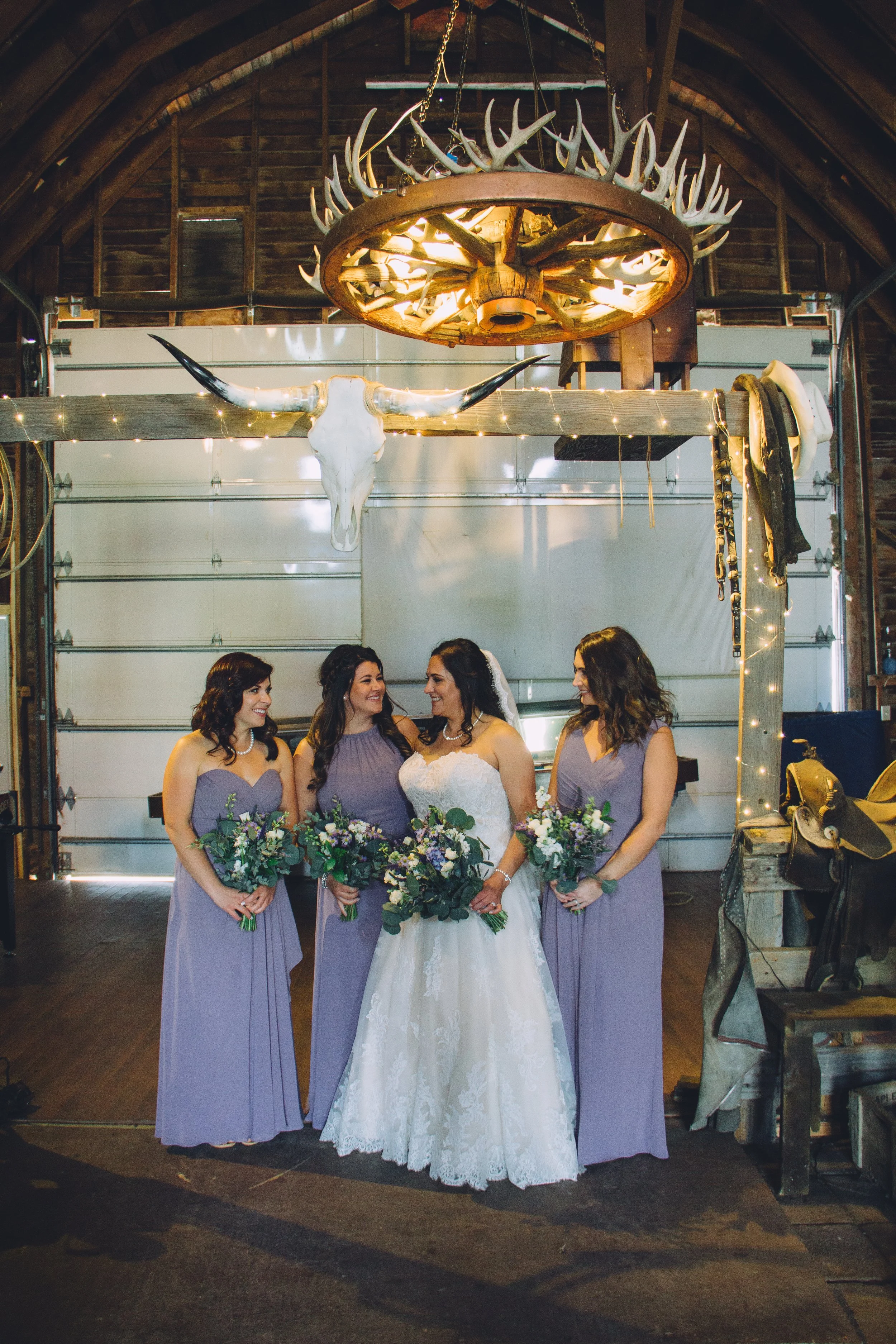 Bride and bridesmaids standing at the entrance to the dance floor beneath an antler chandelier