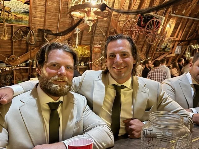Two groomsmen sitting together at the rustic bar