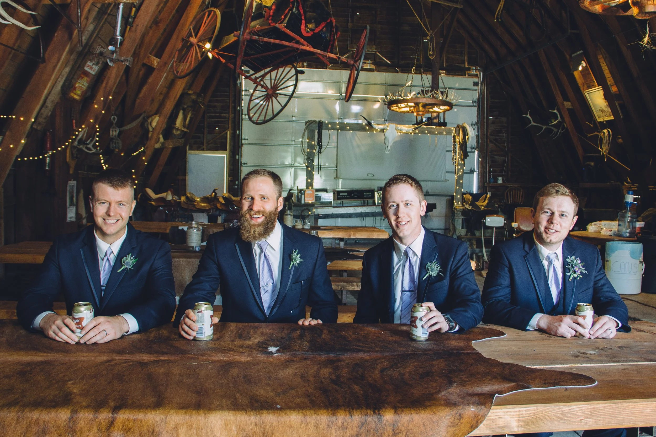 Four groomsmen seated at handmade picnic table