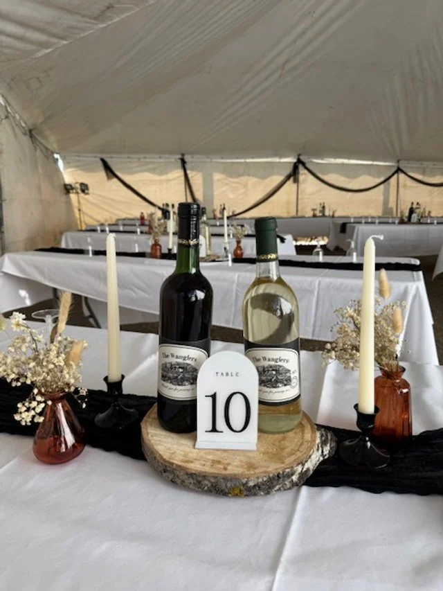 Rustic wooden table centerpiece with a wine bottle and table runner.