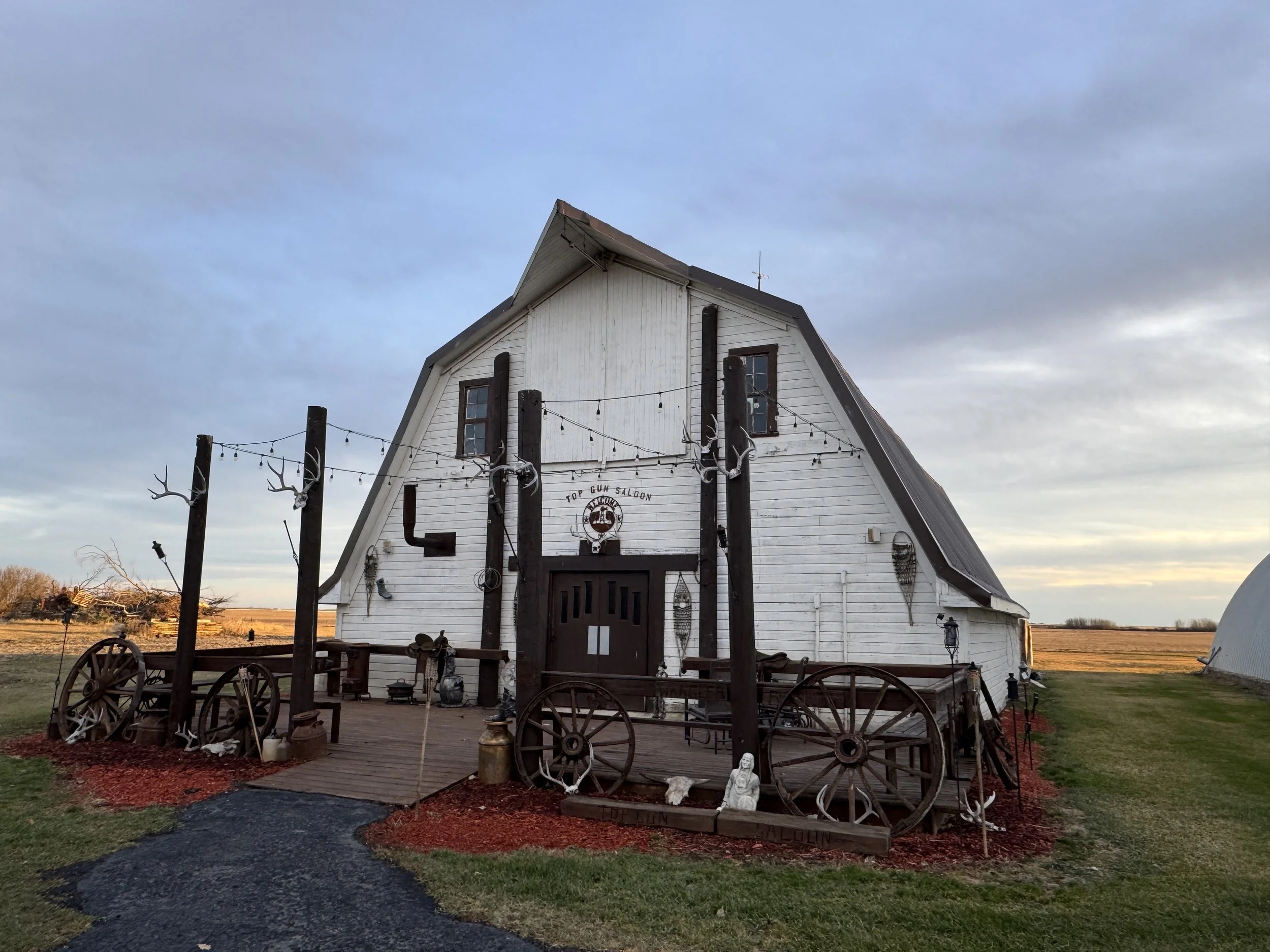 Evening view of the barn featuring wagon wheels, rustic lighting, and western charm.