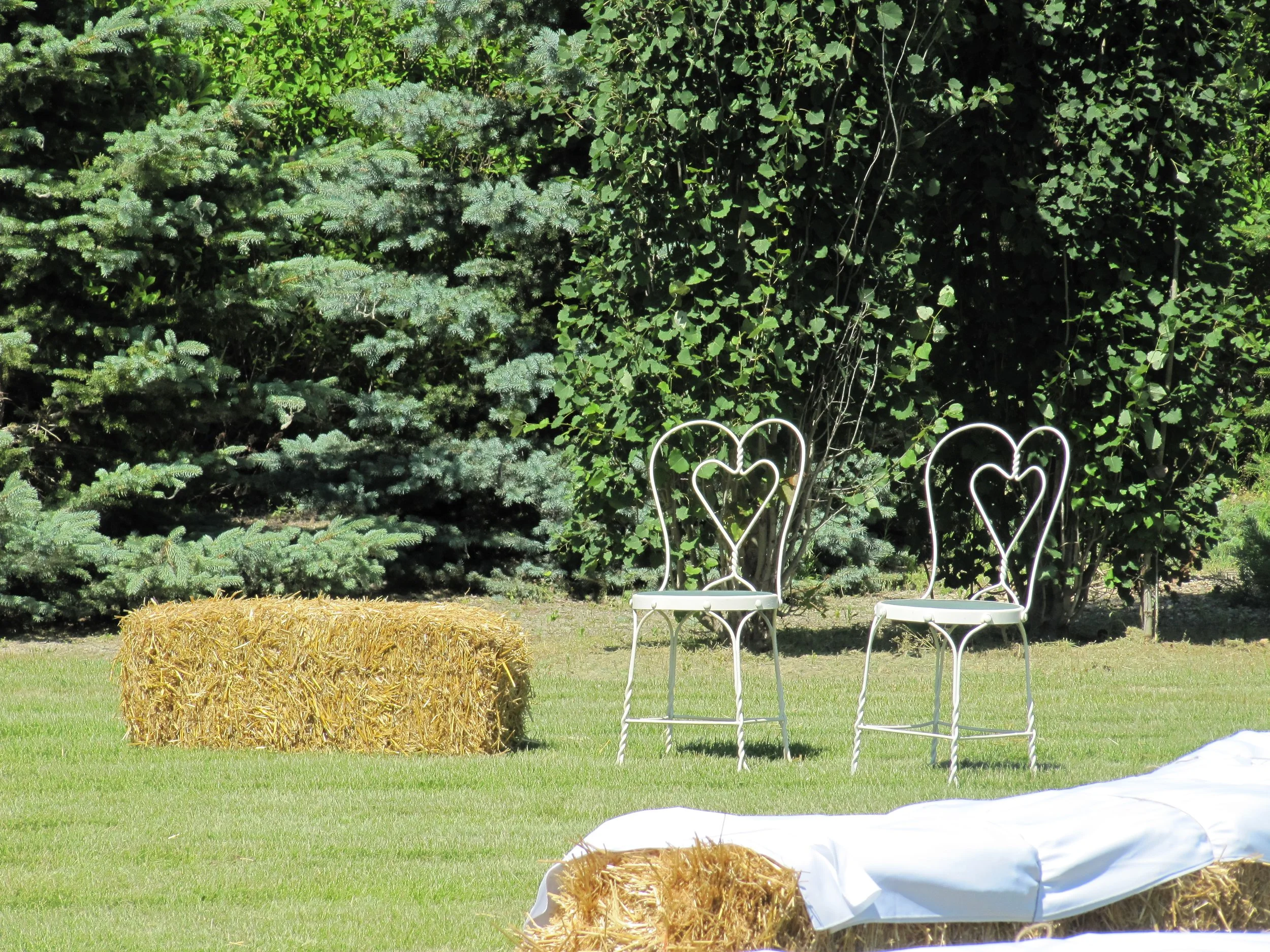 Rustic ceremony seating featuring hay bales and special seating for bride and groom.