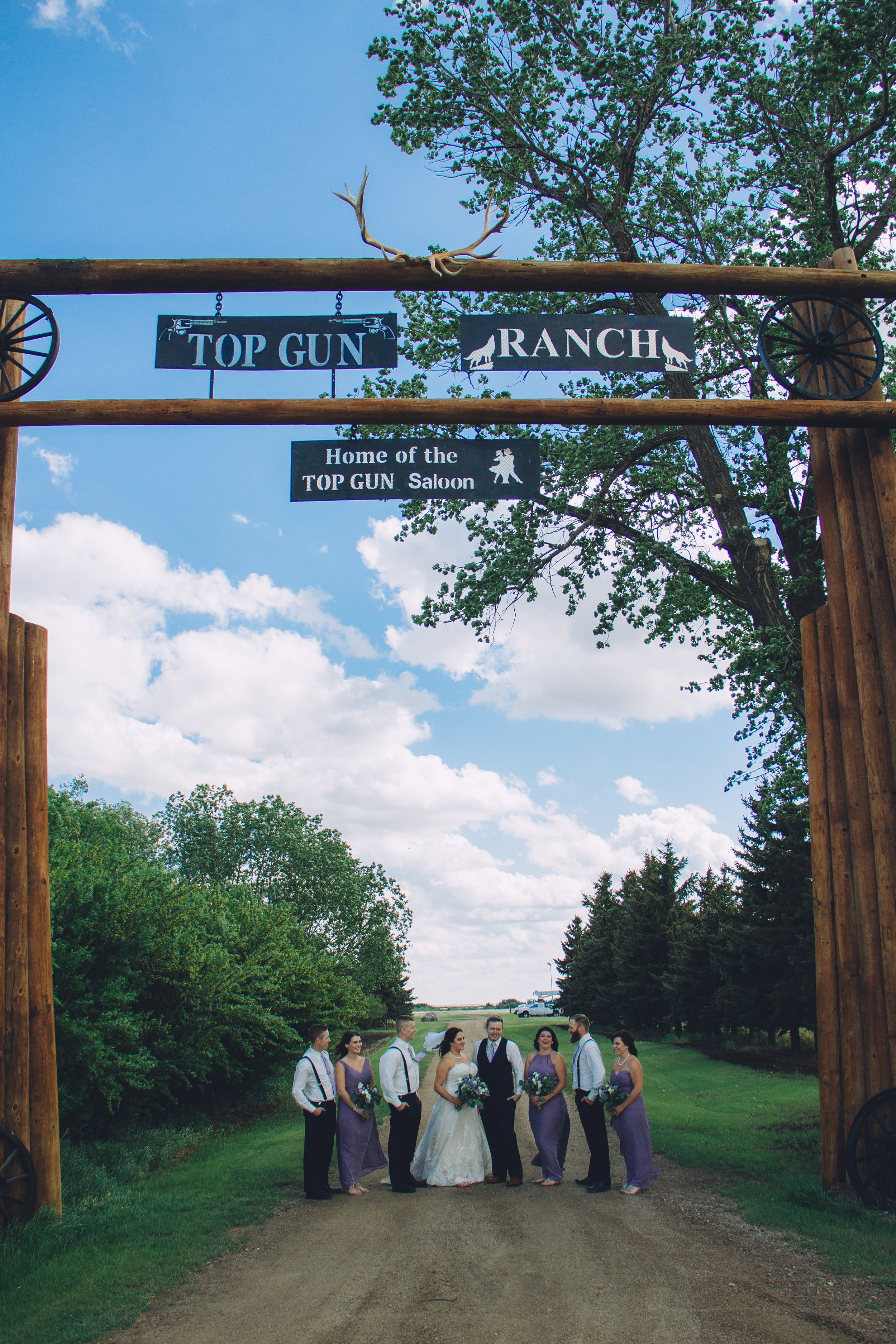 Wedding party gathered beneath the entrance archway at Top Gun Saloon