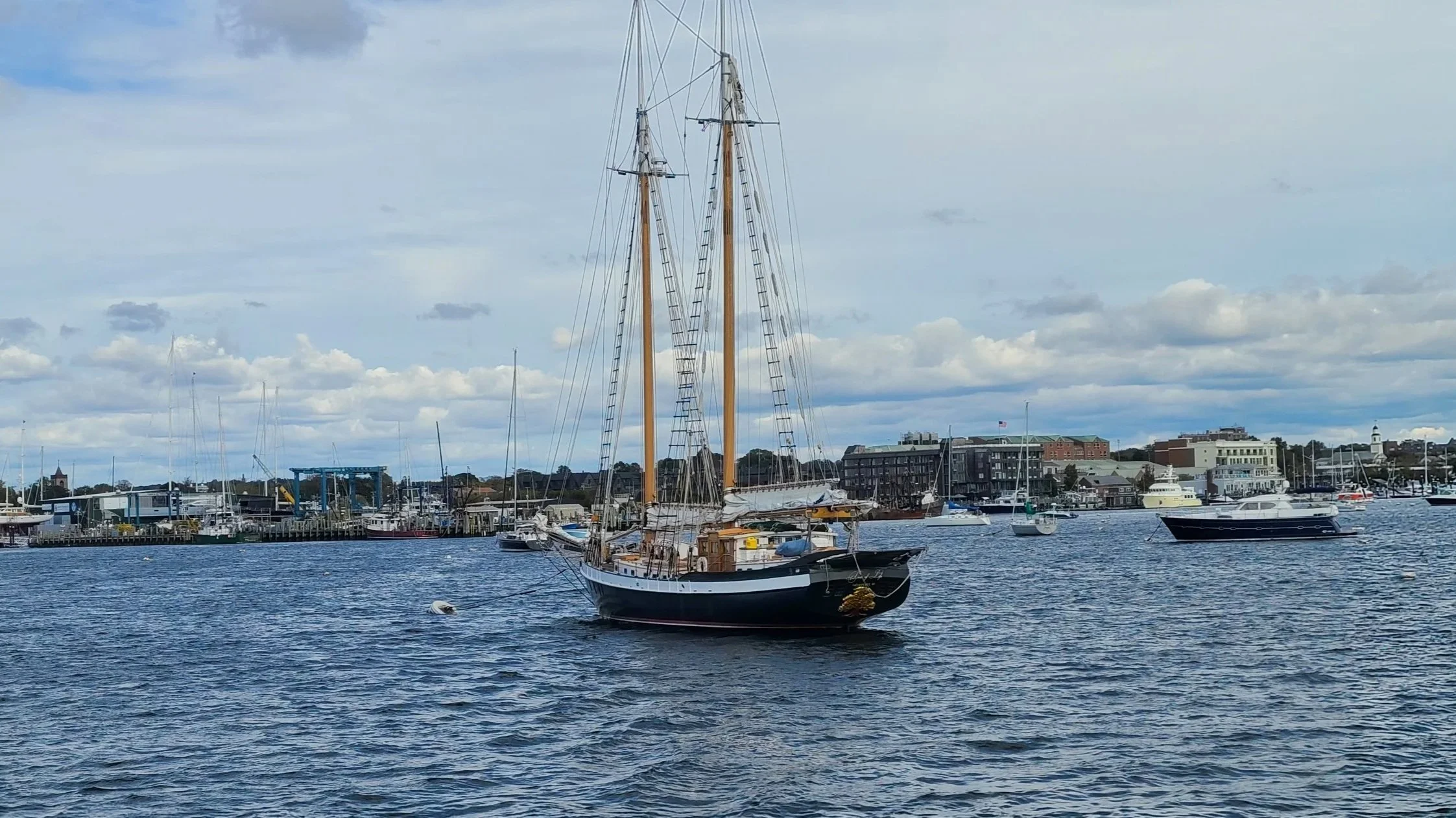 Two-masted schooner sailing through Newport Harbor near the Newport, Rhode Island cruise port and downtown waterfront