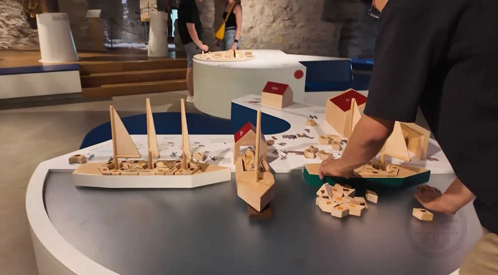 Visitors gathered around an interactive ship-building puzzle exhibit inside the Fat Margaret Maritime Museum in Tallinn, Estonia.