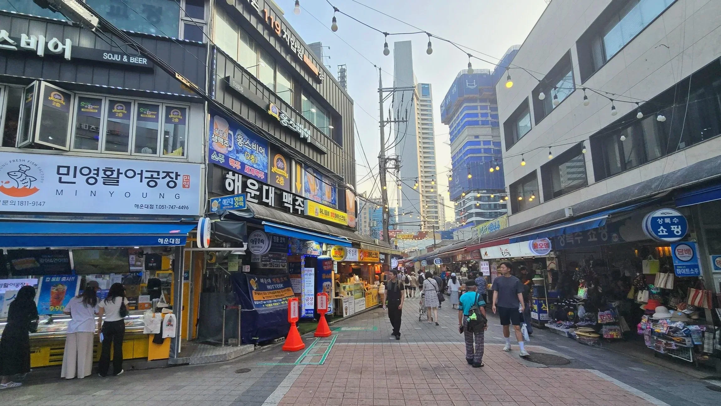 Pedestrians exploring a seafood market street lined with Korean restaurants and shops in Busan, South Korea