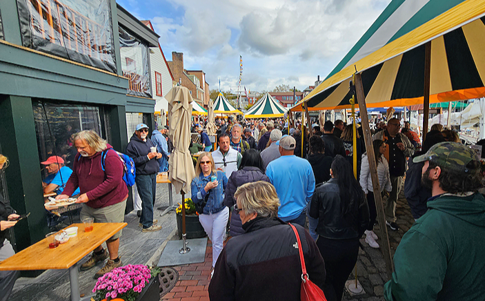 Visitors exploring Bowen’s Wharf in downtown Newport, Rhode Island, with waterfront shops, food stands, and striped tents