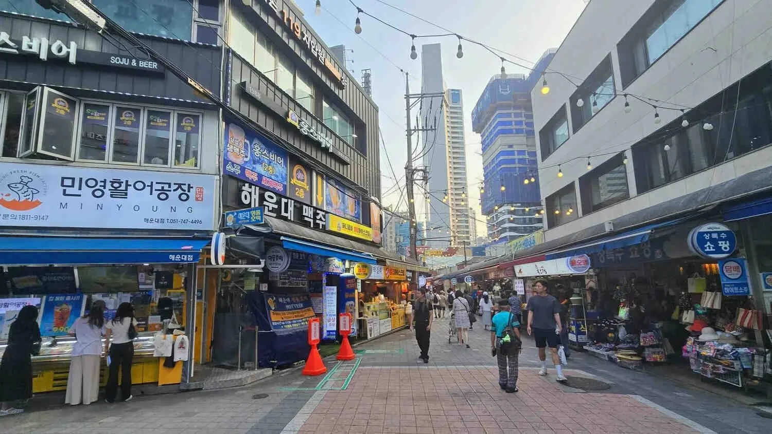 Pedestrians exploring a seafood market street lined with Korean restaurants and shops in Busan, South Korea
