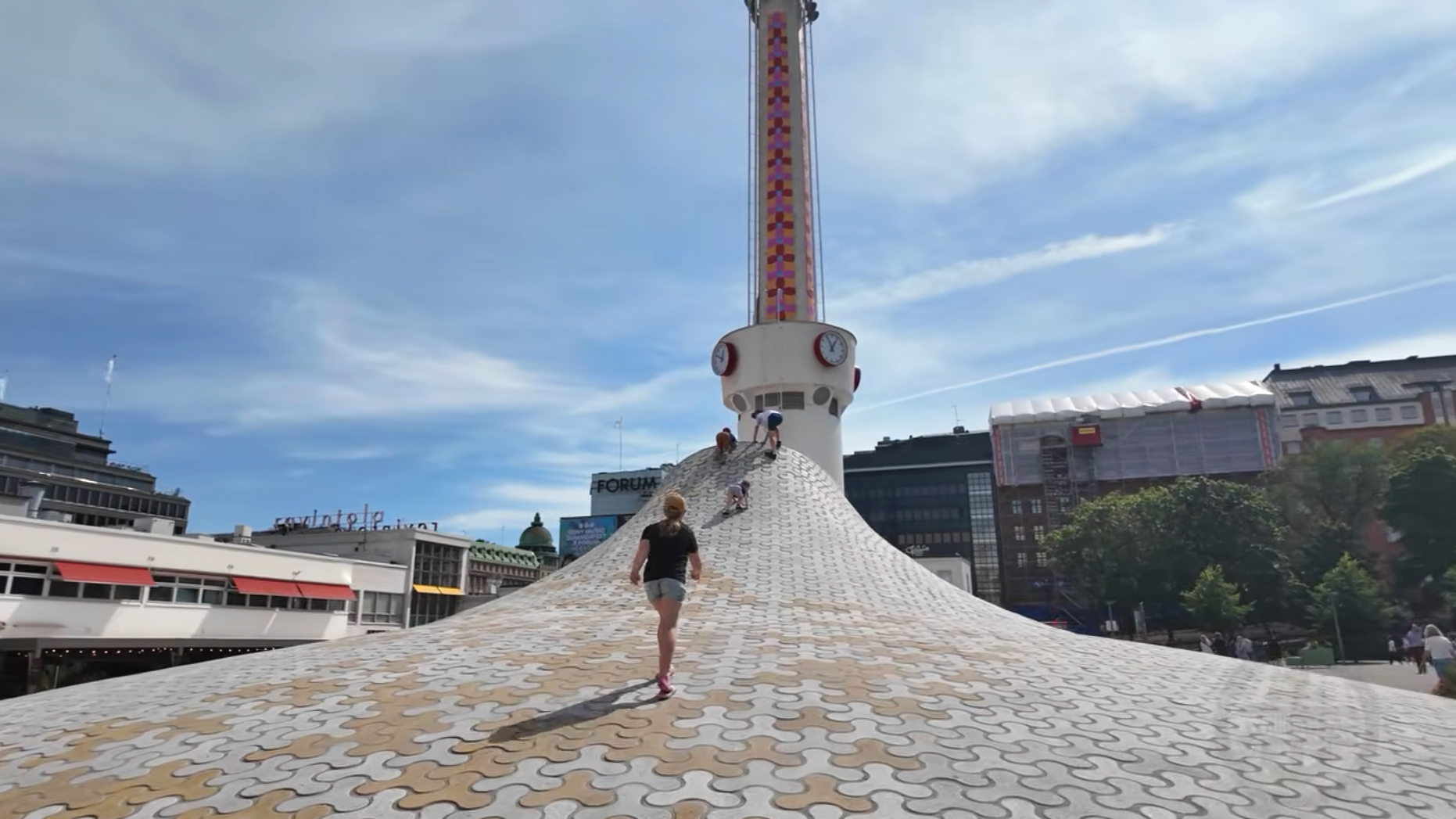 Visitors walking and climbing on the curved Amos Rex rooftop installation with the Lasipalatsi tower in the background.