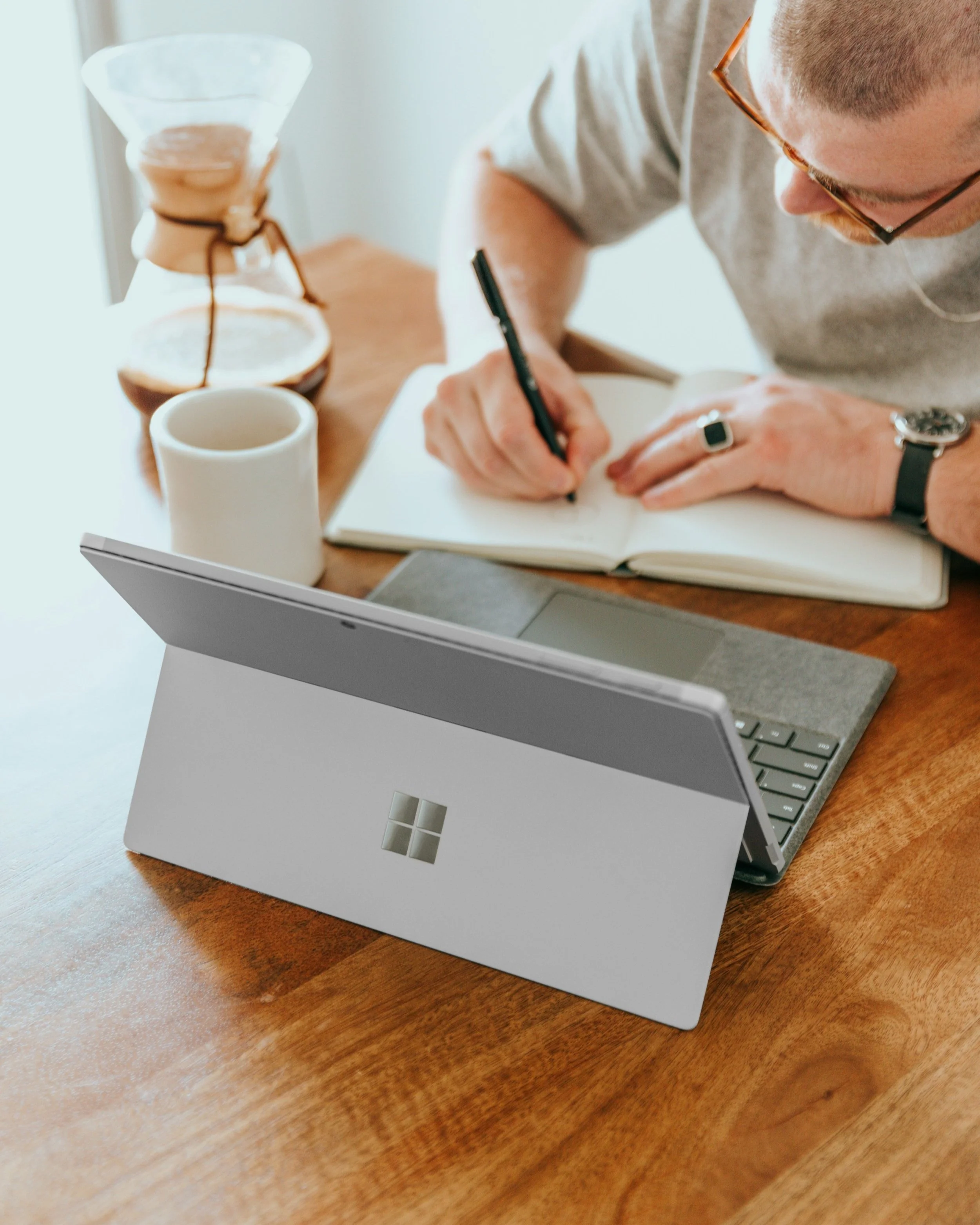 A group presentation in a brick-walled office space, with a speaker pointing at a screen and an audience seated watching attentively.