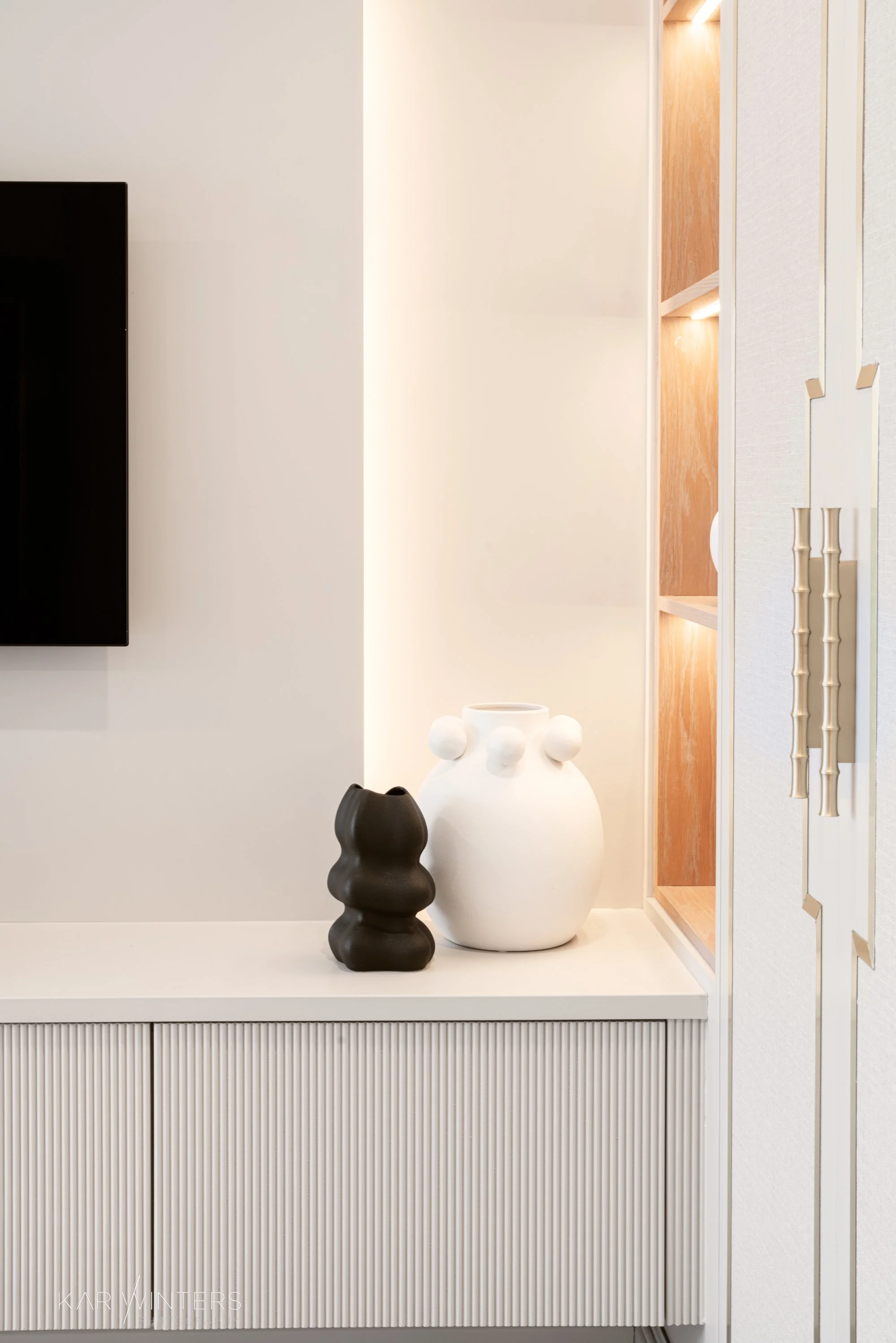 Decorative black and white modern ceramic vases on a white console table in a contemporary living room.